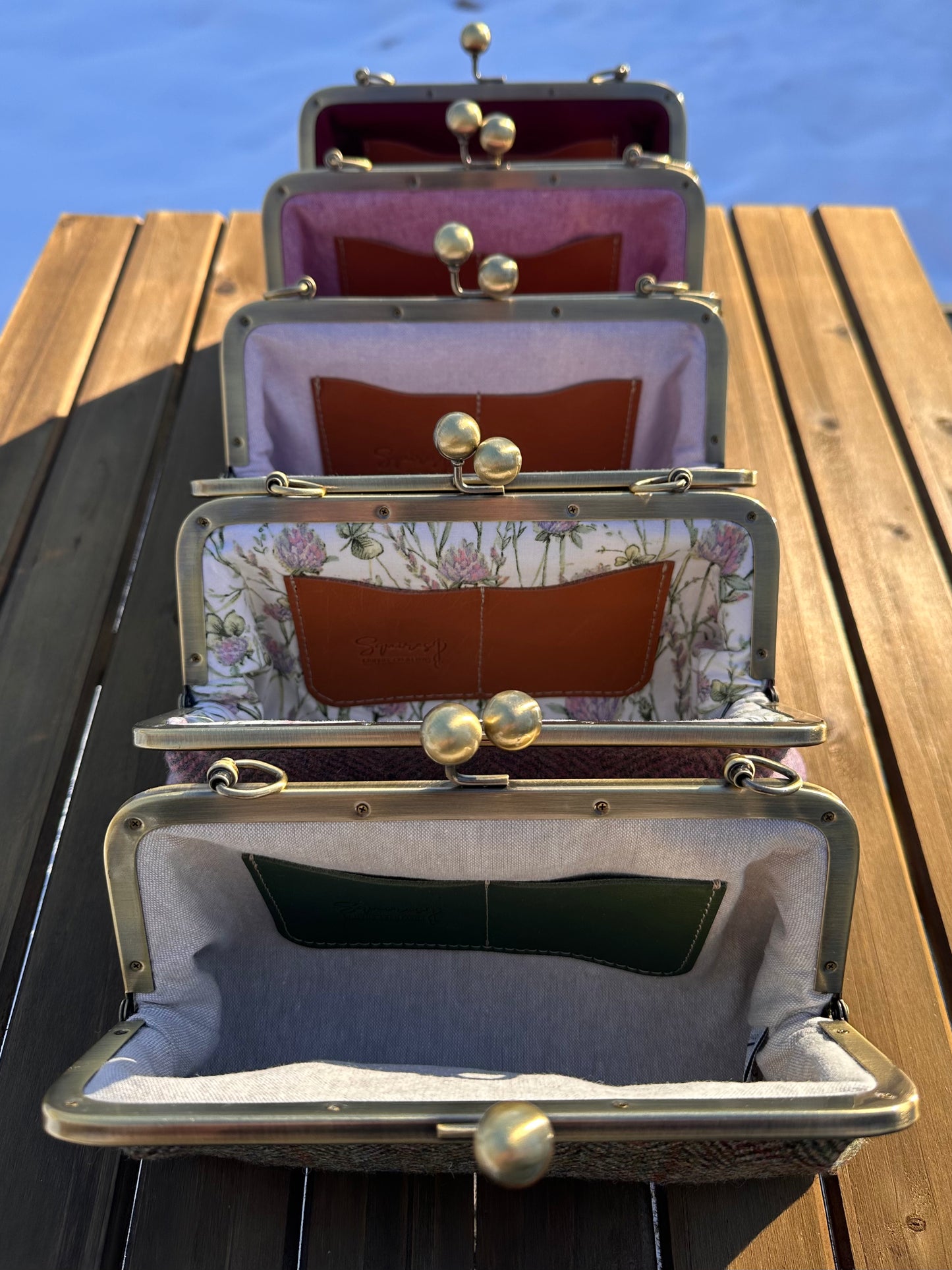 Collection of interior views of Harris Tweed® Smith Island kiss lock purses, showcasing coordinating linings, two card slots, and room for essentials like a phone and small items. Classic construction with handcrafted details.