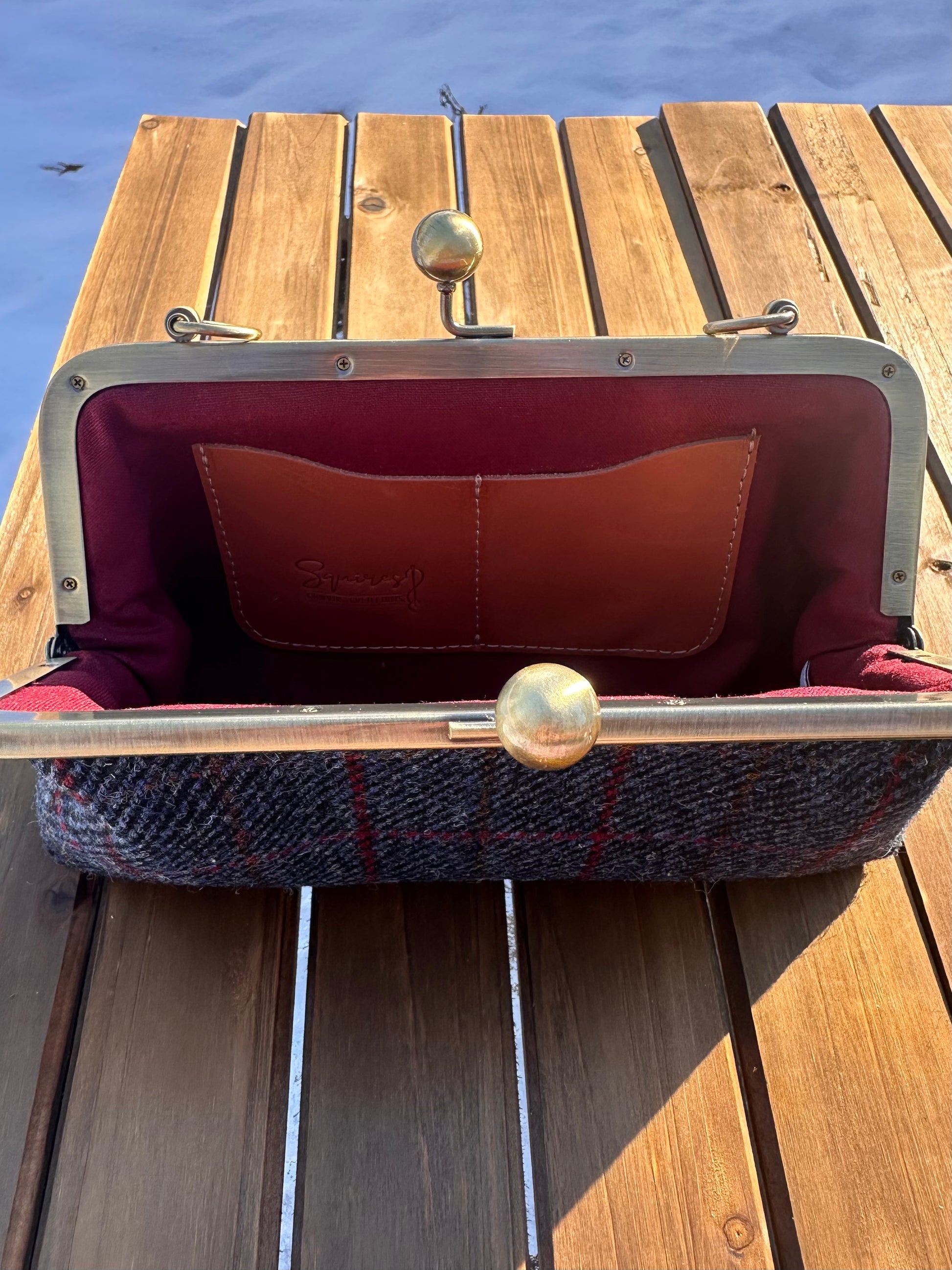 Interior of Dark Navy Plaid Harris Tweed® kiss lock purse. Deep Red Linen lining complements tweed exterior. Bronze hardware, card slots, fits phone and small items.
