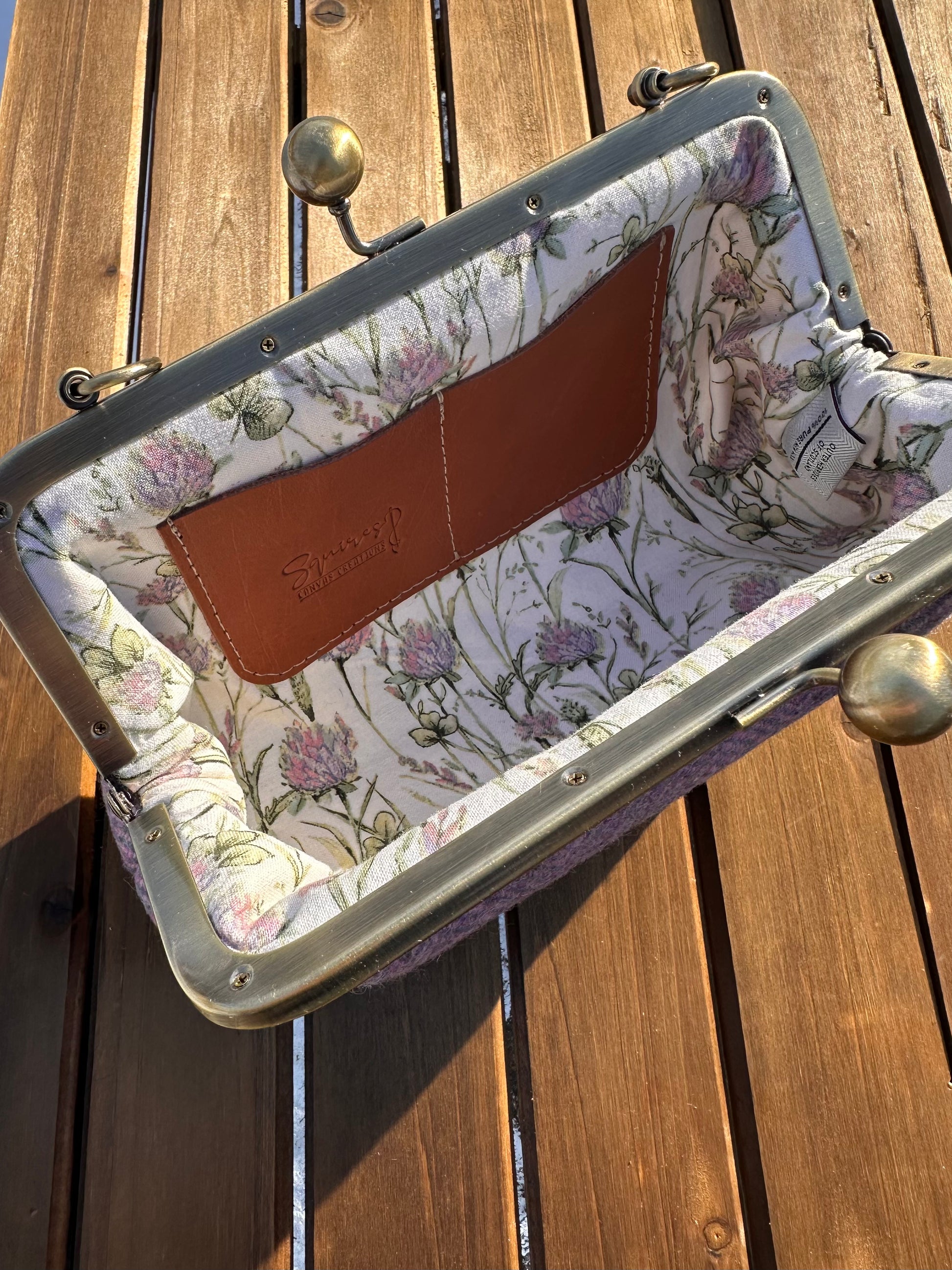Interior of Pink & Blue Harris Tweed® kiss lock purse. Floral lining complements tweed exterior. Bronze hardware, card slots, fits phone and small items.
