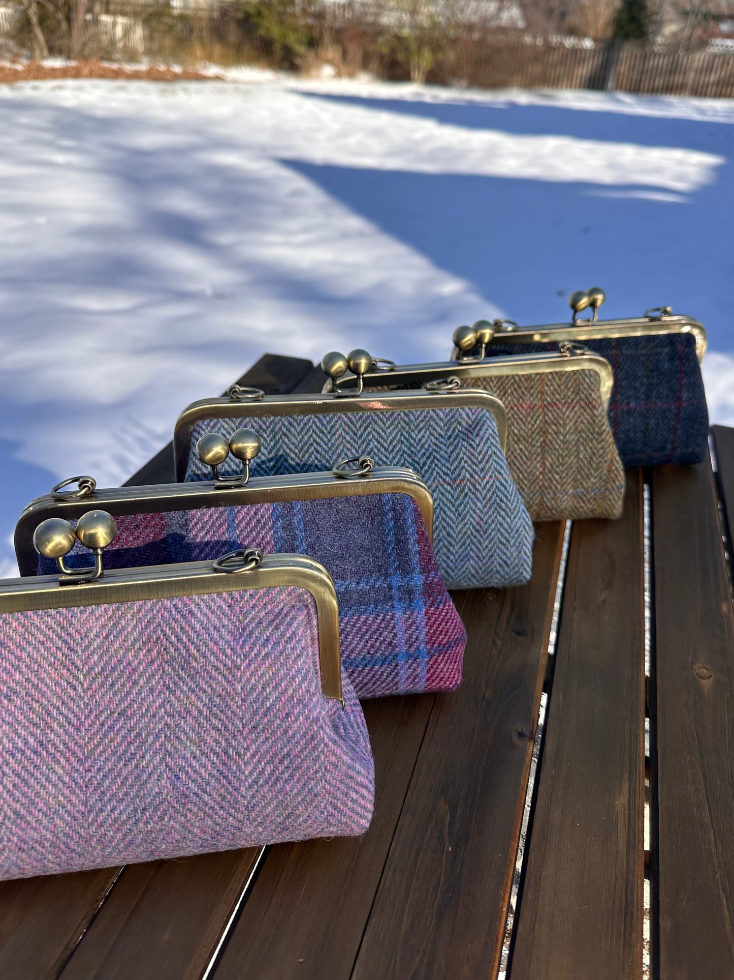 Collection of handcrafted Harris Tweed® kiss lock purses with bronze hardware. Classic clutch style with 2 card slots, fits a phone and small essentials. Wear as a clutch, shoulder bag, or crossbody. Made in Maryland, perfect for special occasions.