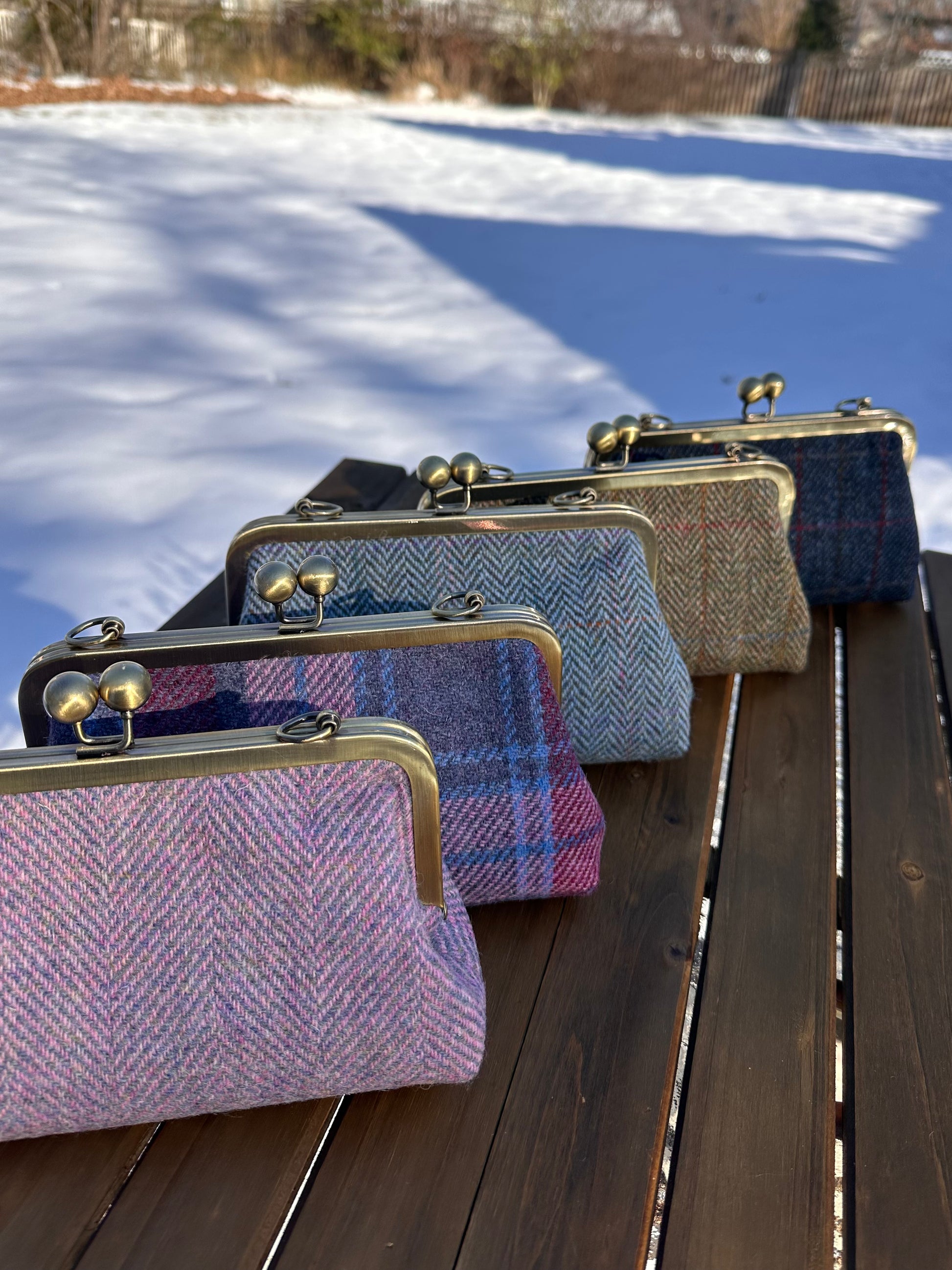 Collection of handcrafted Harris Tweed® kiss lock purses with bronze hardware. Classic clutch style with 2 card slots, fits a phone and small essentials. Wear as a clutch, shoulder bag, or crossbody. Made in Maryland, perfect for special occasions.