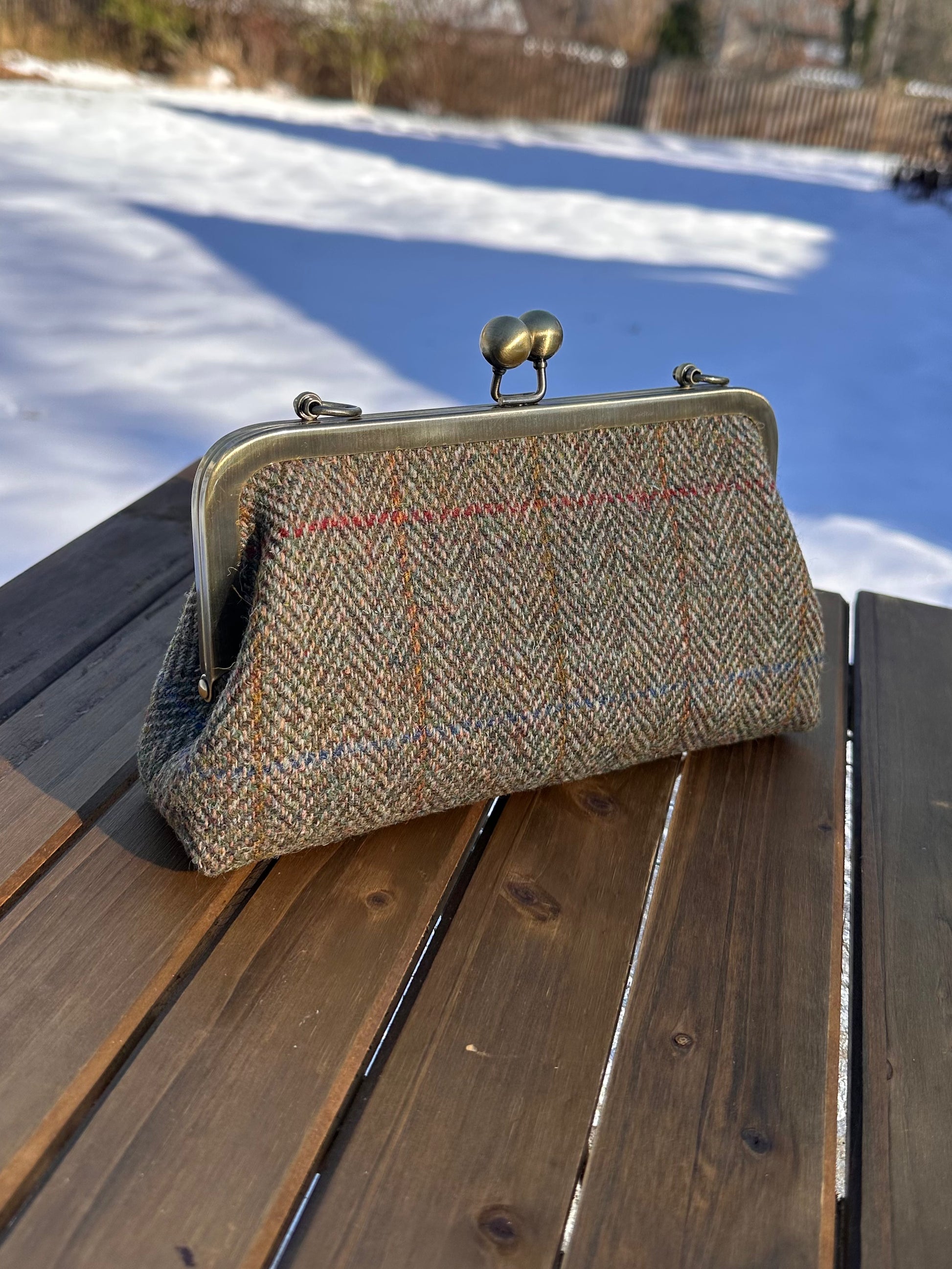 Harris Tweed® kiss lock purse in Green Mix Herringbone with bronze hardware. Wear as a clutch, attach chain for shoulder or crossbody wear. Holds phone, cards, and small items. Timeless design handcrafted in Maryland.
