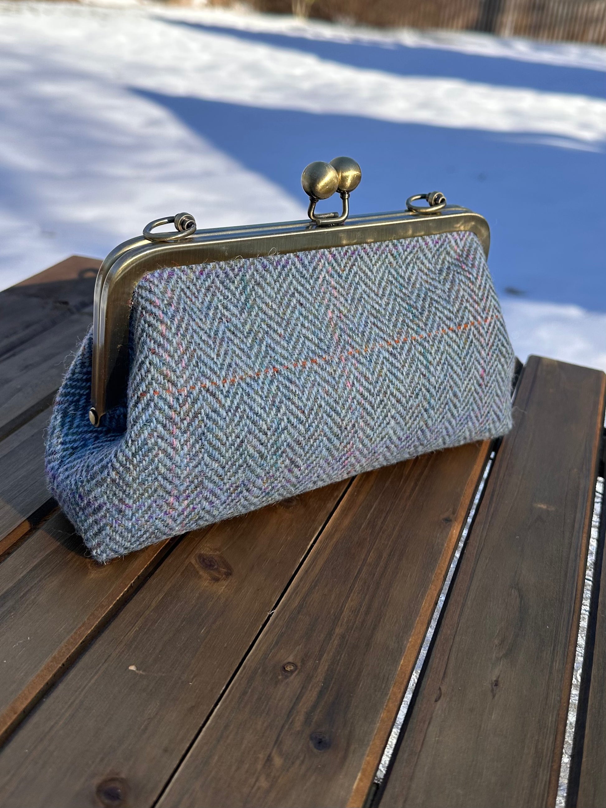 Harris Tweed® kiss lock purse in Blue Herringbone with bronze hardware. Wear as a clutch, attach chain for shoulder or crossbody wear. Holds phone, cards, and small items. Timeless design handcrafted in Maryland.