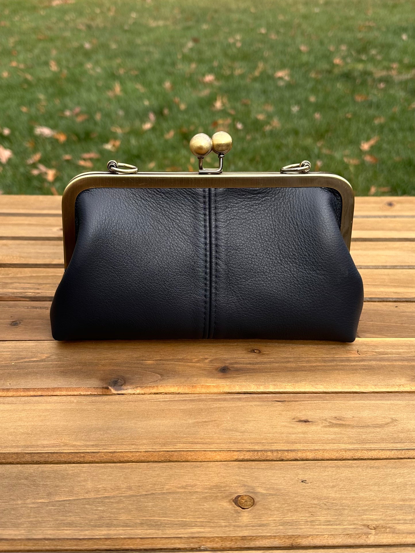 Leather kiss lock purse in Black with bronze hardware. Wear as a clutch, crossbody, or shoulder bag. Holds phone, cards, and essentials. Made in Maryland.