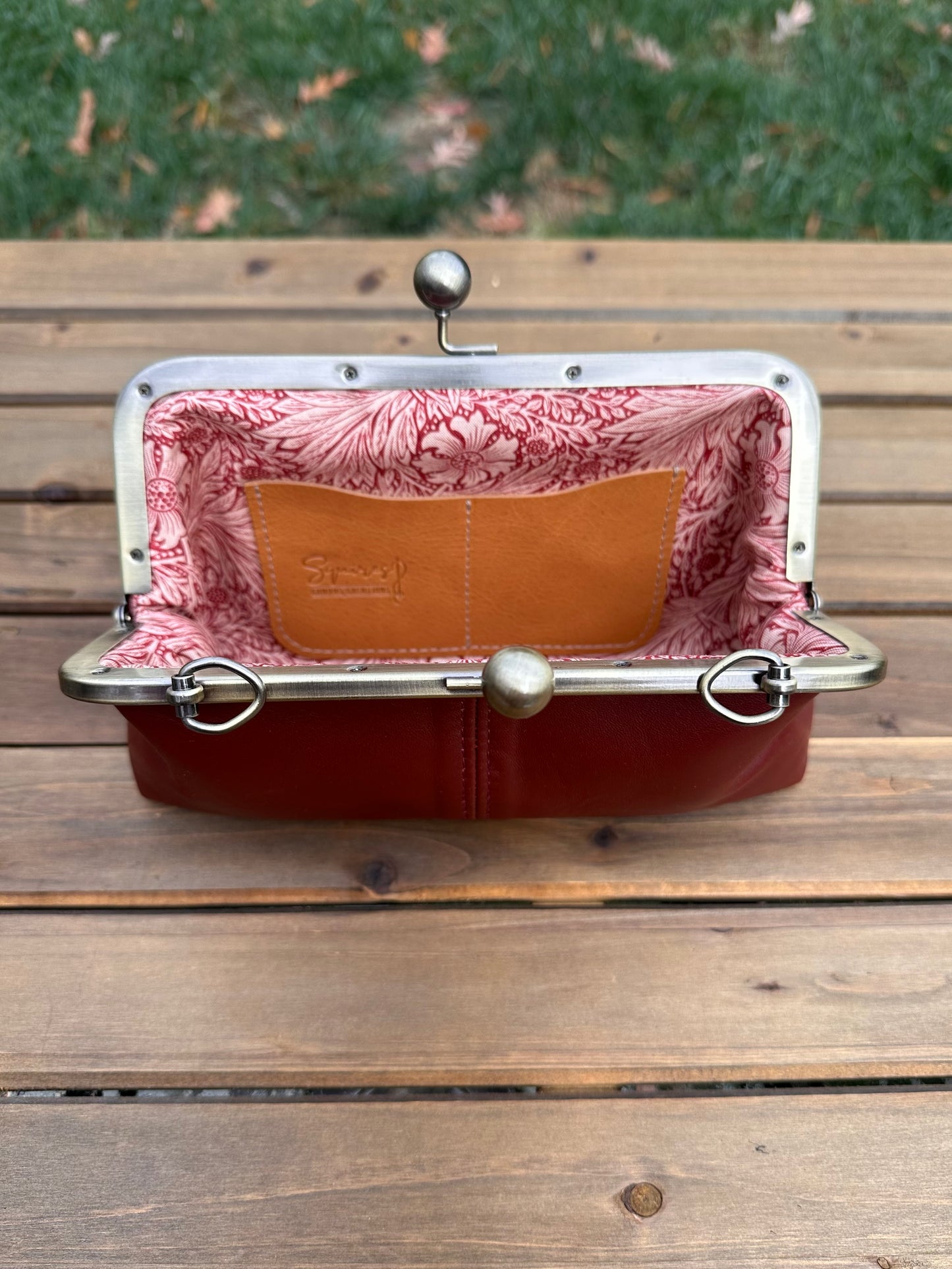 Interior of Burgundy leather kiss lock purse with Pink Floral lining. Includes 2 card slots and space for phone and essentials. Compact and functional design. Made in Maryland.