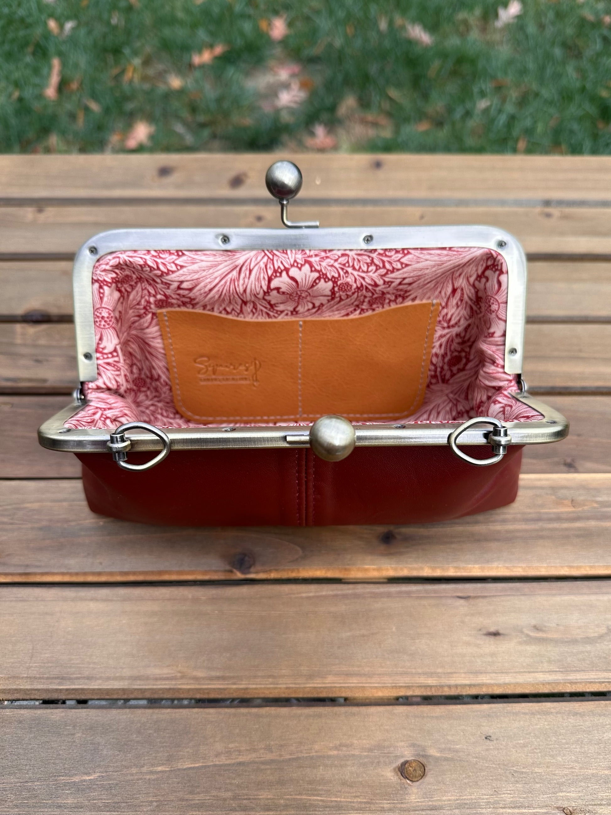 Interior of Burgundy leather kiss lock purse with Pink Floral lining. Includes 2 card slots and space for phone and essentials. Compact and functional design. Made in Maryland.