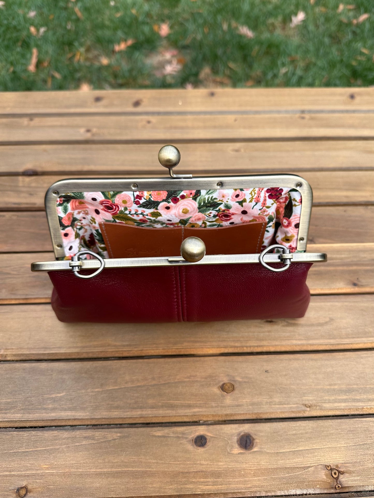 Interior of Burgundy leather kiss lock purse with Pink Flower lining. Includes 2 card slots and space for phone and essentials. Compact and functional design. Made in Maryland.