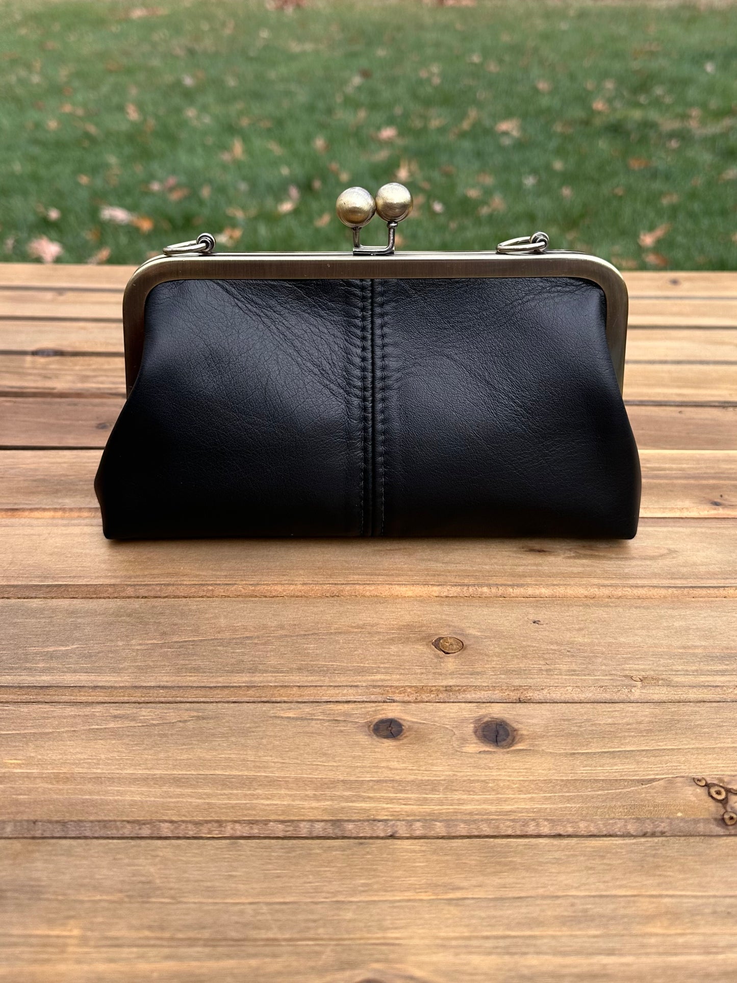 Leather kiss lock purse in Black with bronze hardware. Wear as a clutch, crossbody, or shoulder bag. Holds phone, cards, and essentials. Made in Maryland.