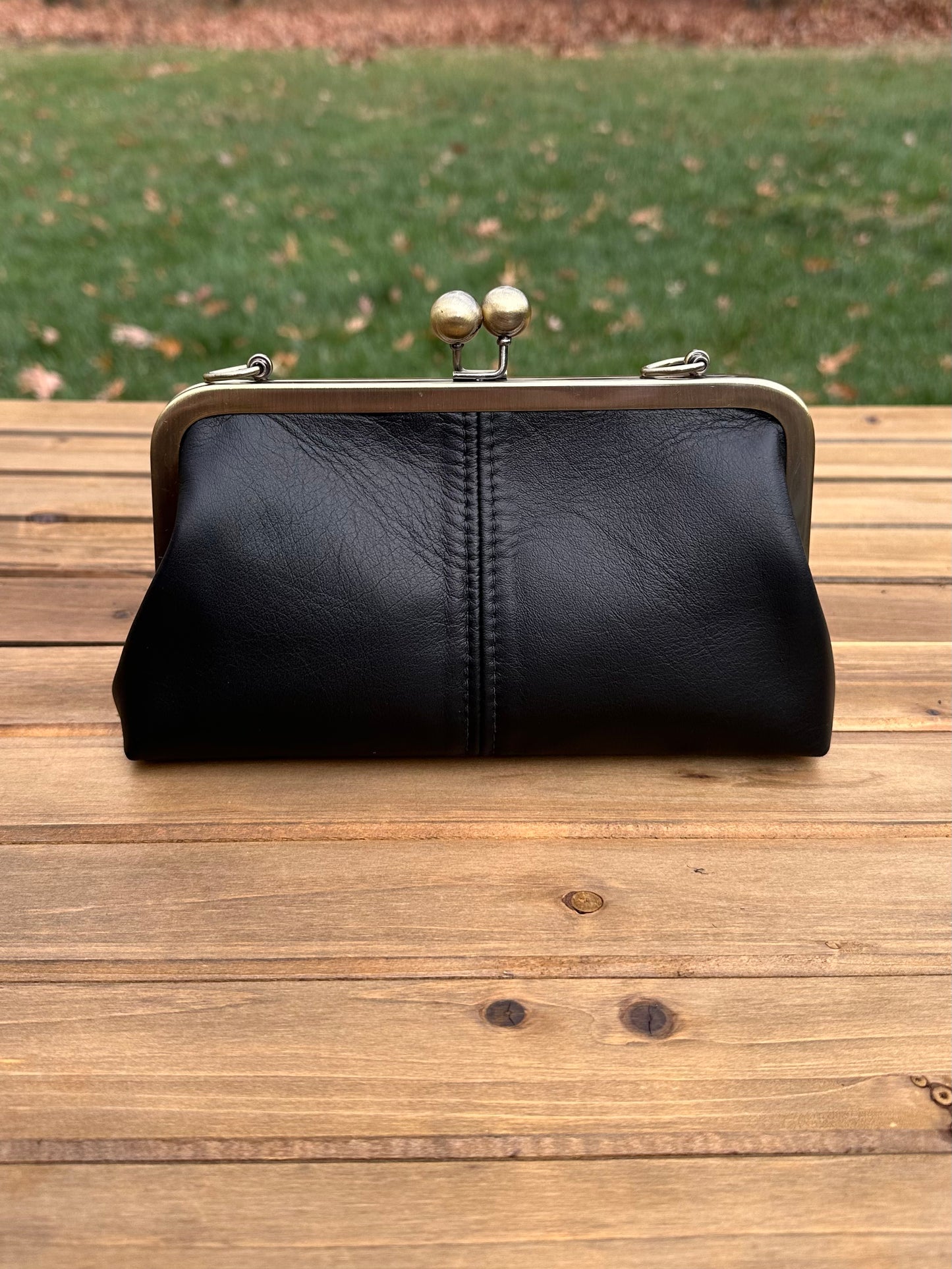 Leather kiss lock purse in Black with bronze hardware. Wear as a clutch, crossbody, or shoulder bag. Holds phone, cards, and essentials. Made in Maryland.