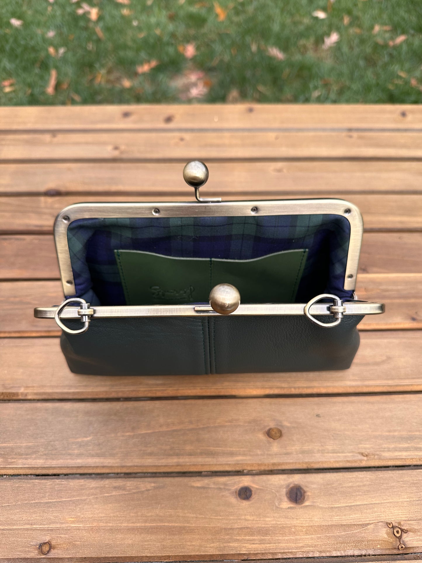 Interior of Dark Forest Green leather kiss lock purse with Green Plaid lining. Includes 2 card slots and space for phone and essentials. Compact and functional design. Made in Maryland.