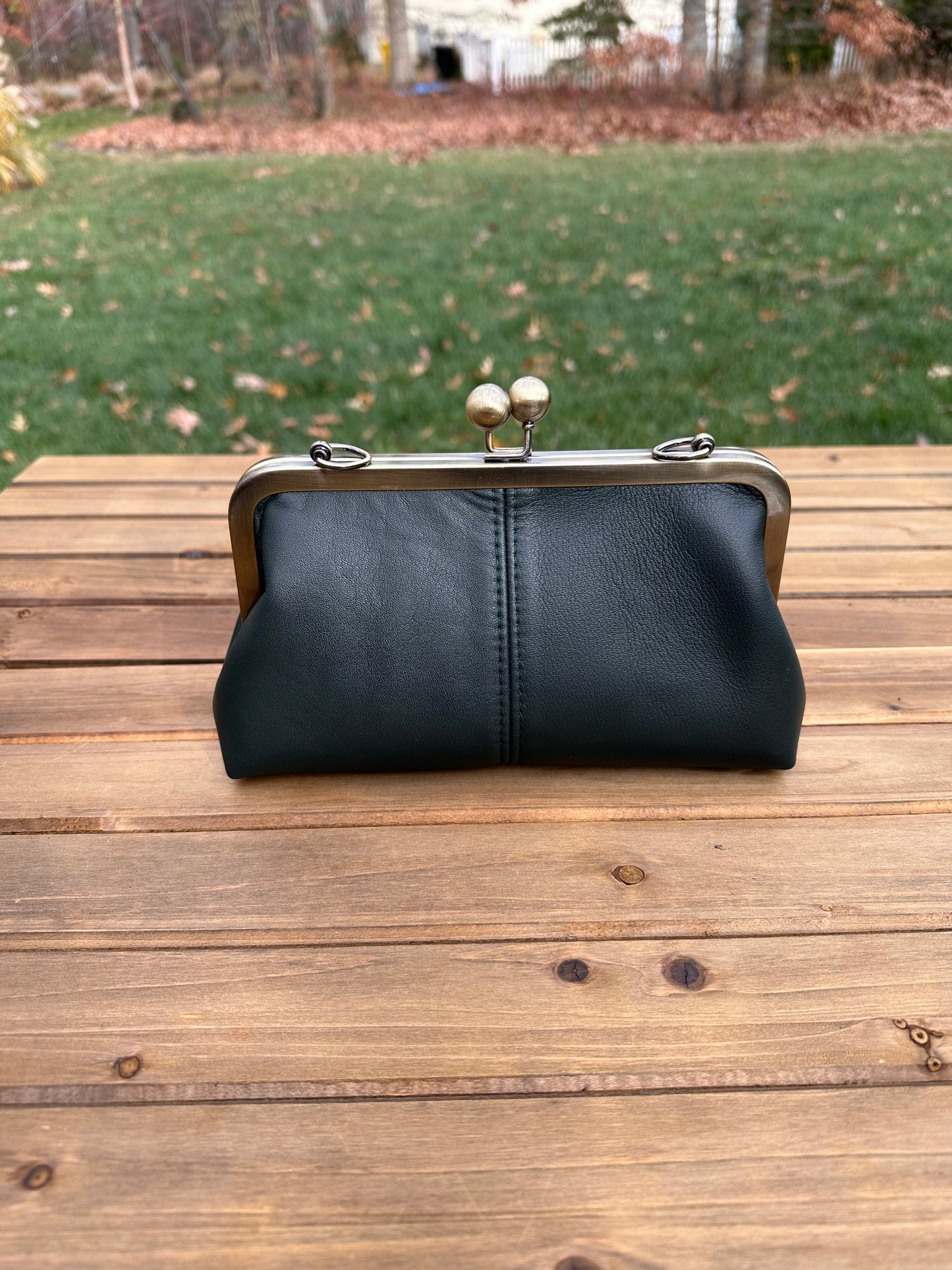 Black Leather kiss lock purse with bronze hardware. Wear as a clutch, crossbody, or shoulder bag. Holds phone, cards, and essentials. Made in Maryland.