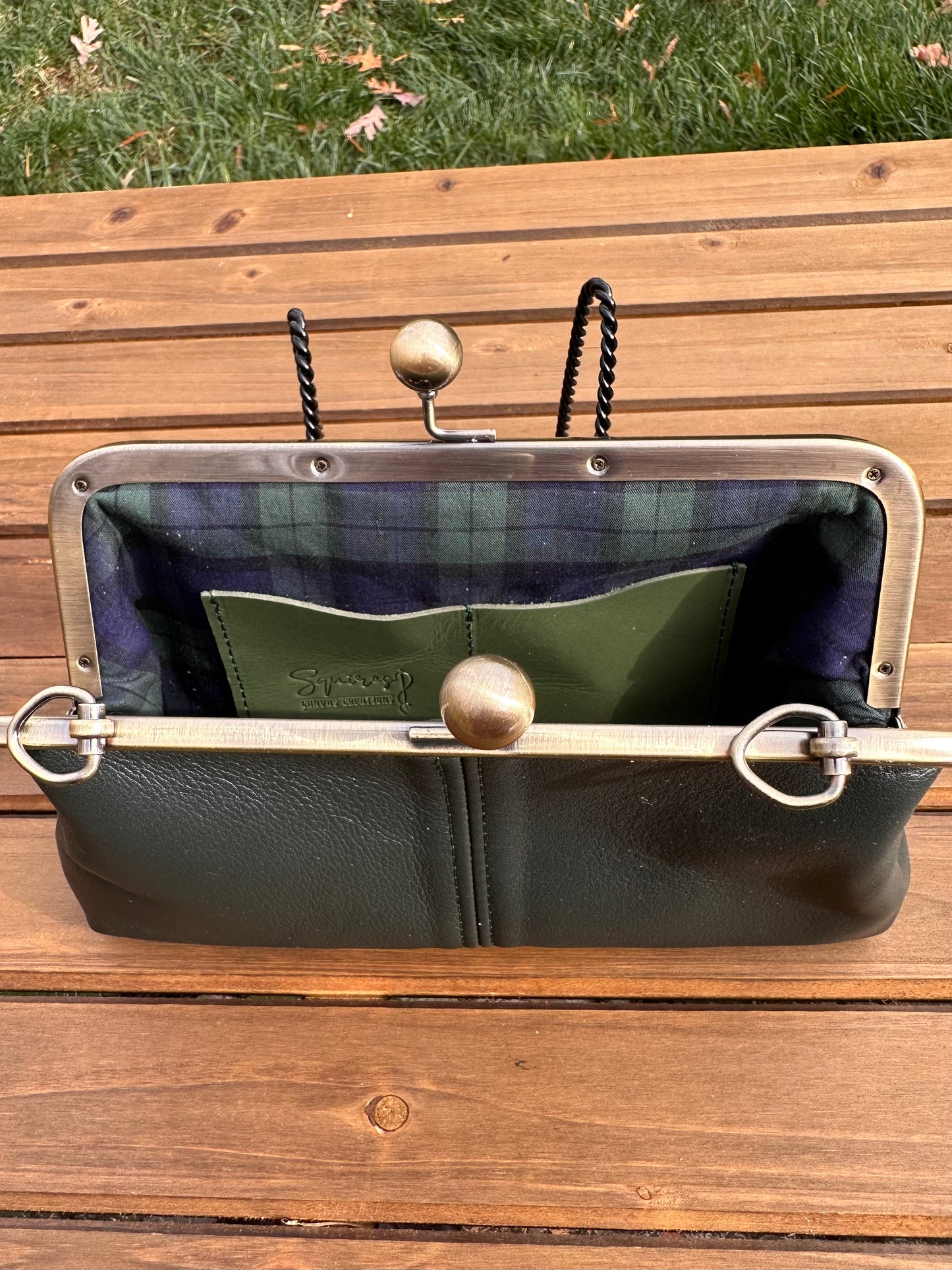 Interior of Dark Forest Green leather kiss lock purse with Navy and Green Plaid lining. Includes 2 card slots and space for phone and essentials. Compact and functional design. Made in Maryland.