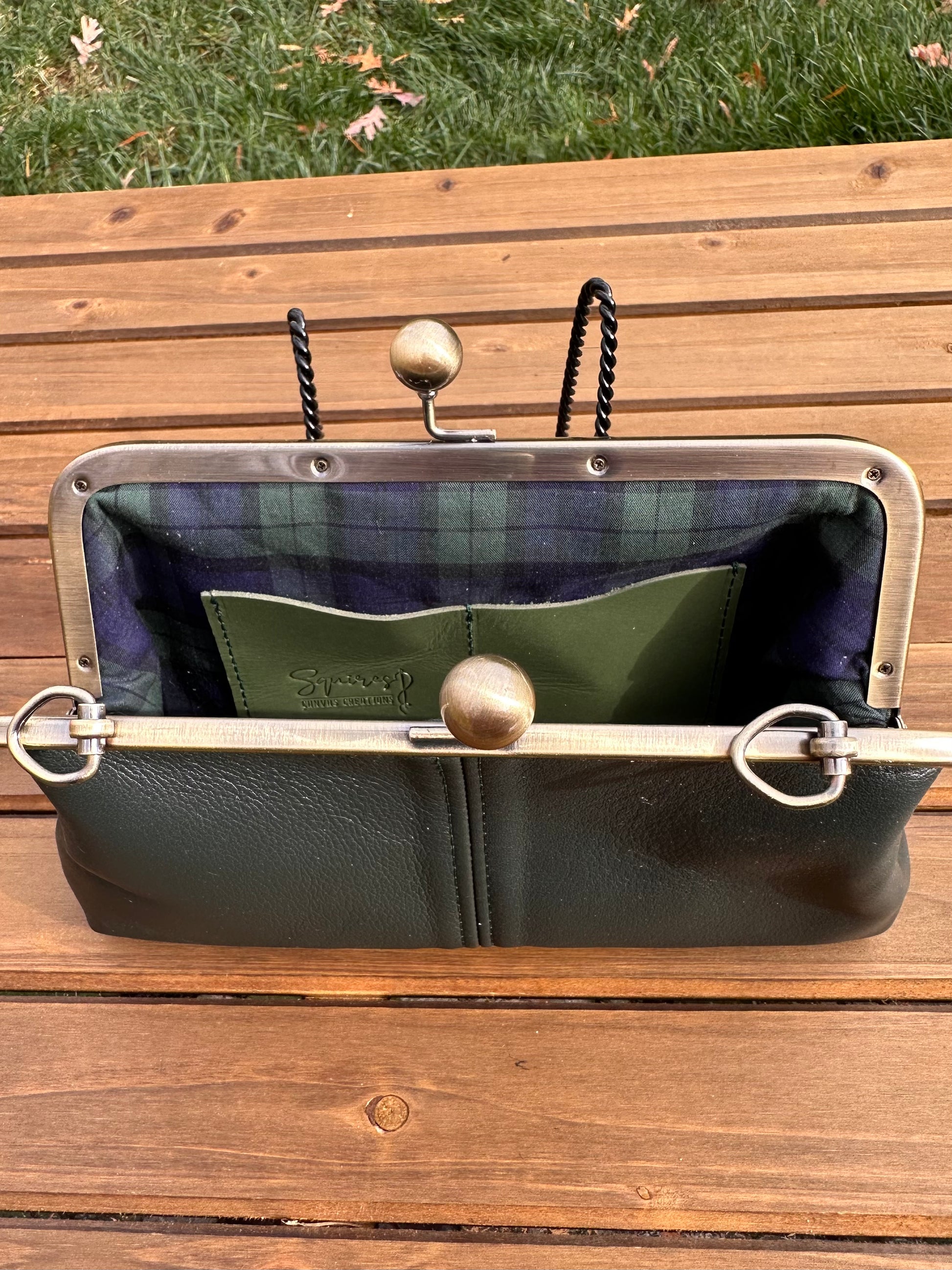 Interior of Dark Forest Green leather kiss lock purse with Navy and Green Plaid lining. Includes 2 card slots and space for phone and essentials. Compact and functional design. Made in Maryland.