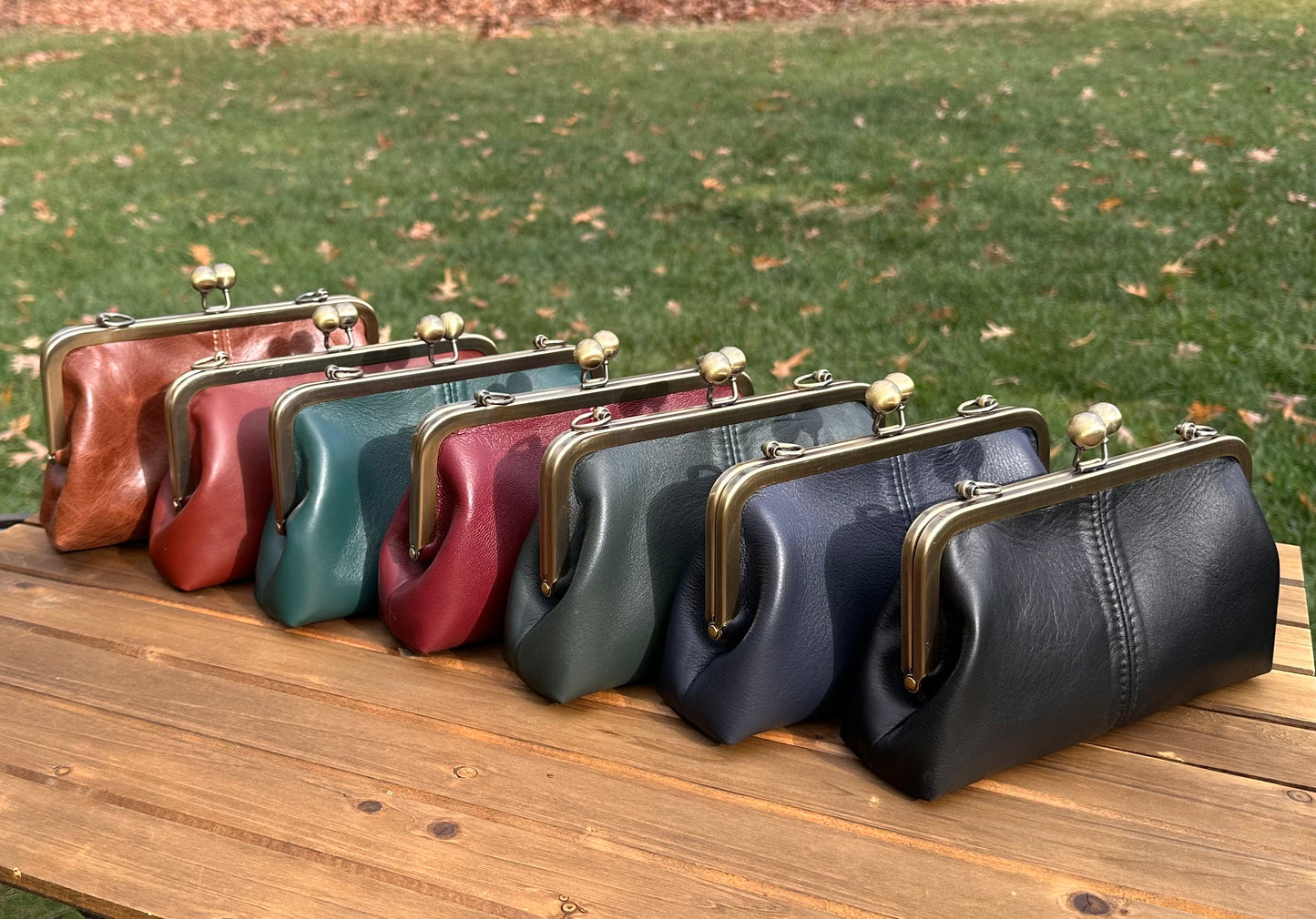 Collection of handcrafted leather kiss lock purses with bronze hardware and chain straps. Wear as clutch, shoulder, or crossbody. Made in Maryland.