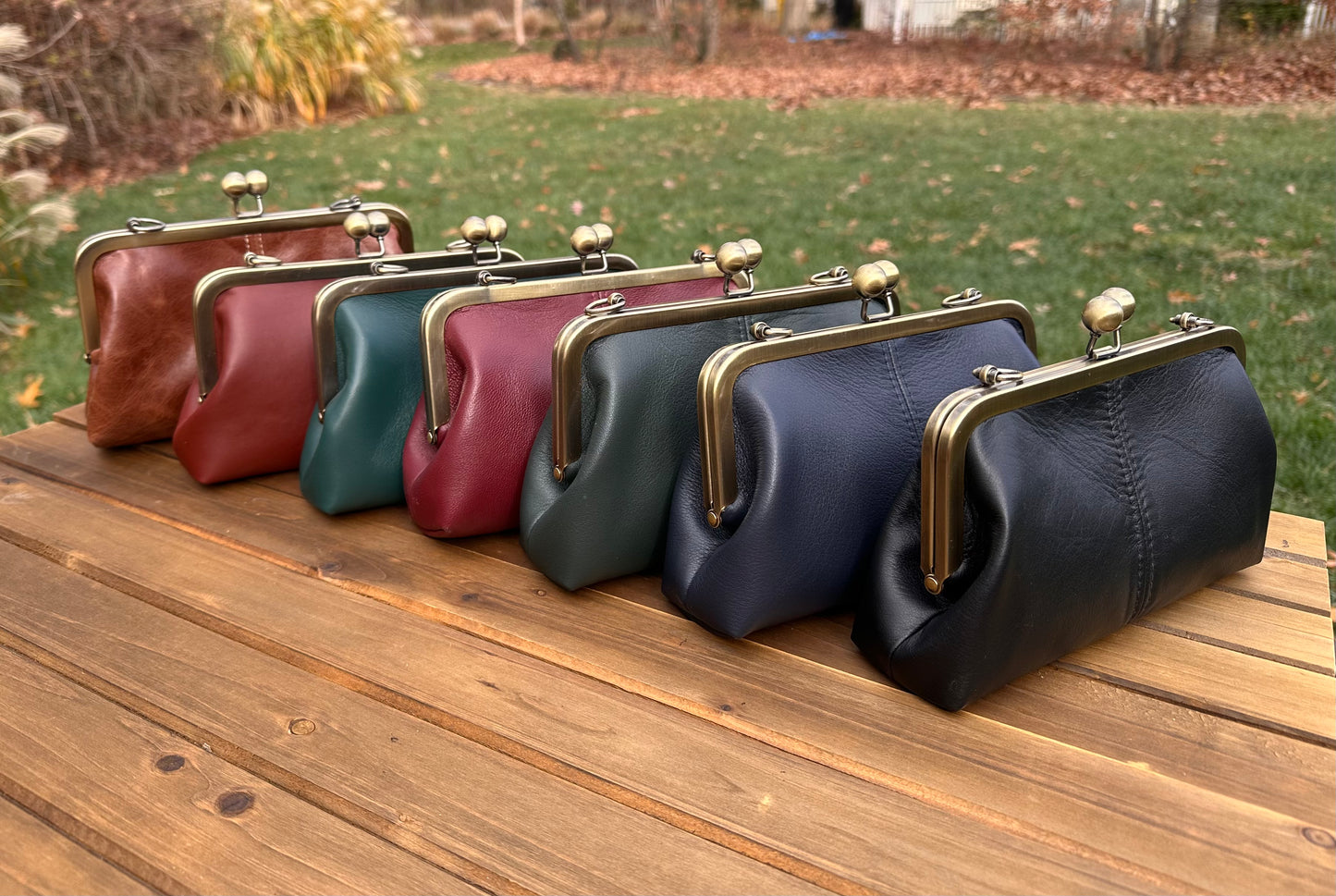 Collection of handcrafted leather kiss lock purses with bronze hardware and chain straps. Wear as clutch, shoulder, or crossbody. Made in Maryland.