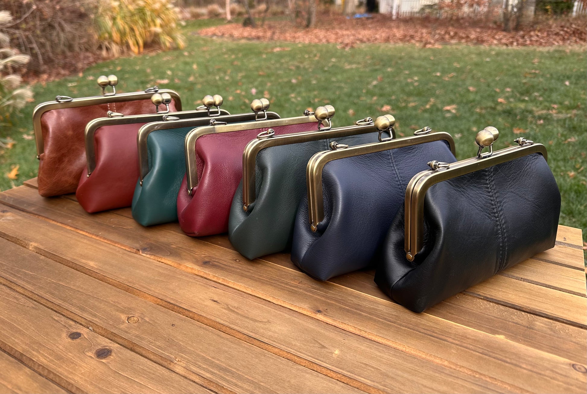 Collection of handcrafted leather kiss lock purses with bronze hardware and chain straps. Wear as clutch, shoulder, or crossbody. Made in Maryland.