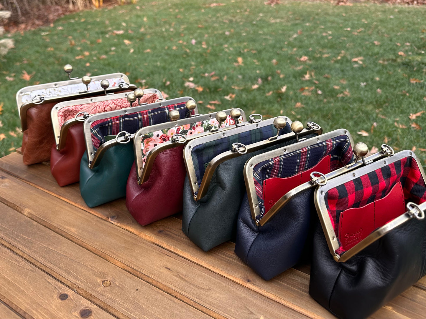 Collection of handcrafted leather kiss lock purses with bronze hardware and chain straps. The interior of leather kiss lock purses with various colorful linings. Includes 2 card slots and space for phone and essentials. Compact and functional design. Wear as clutch, shoulder, or crossbody. Made in Maryland.
