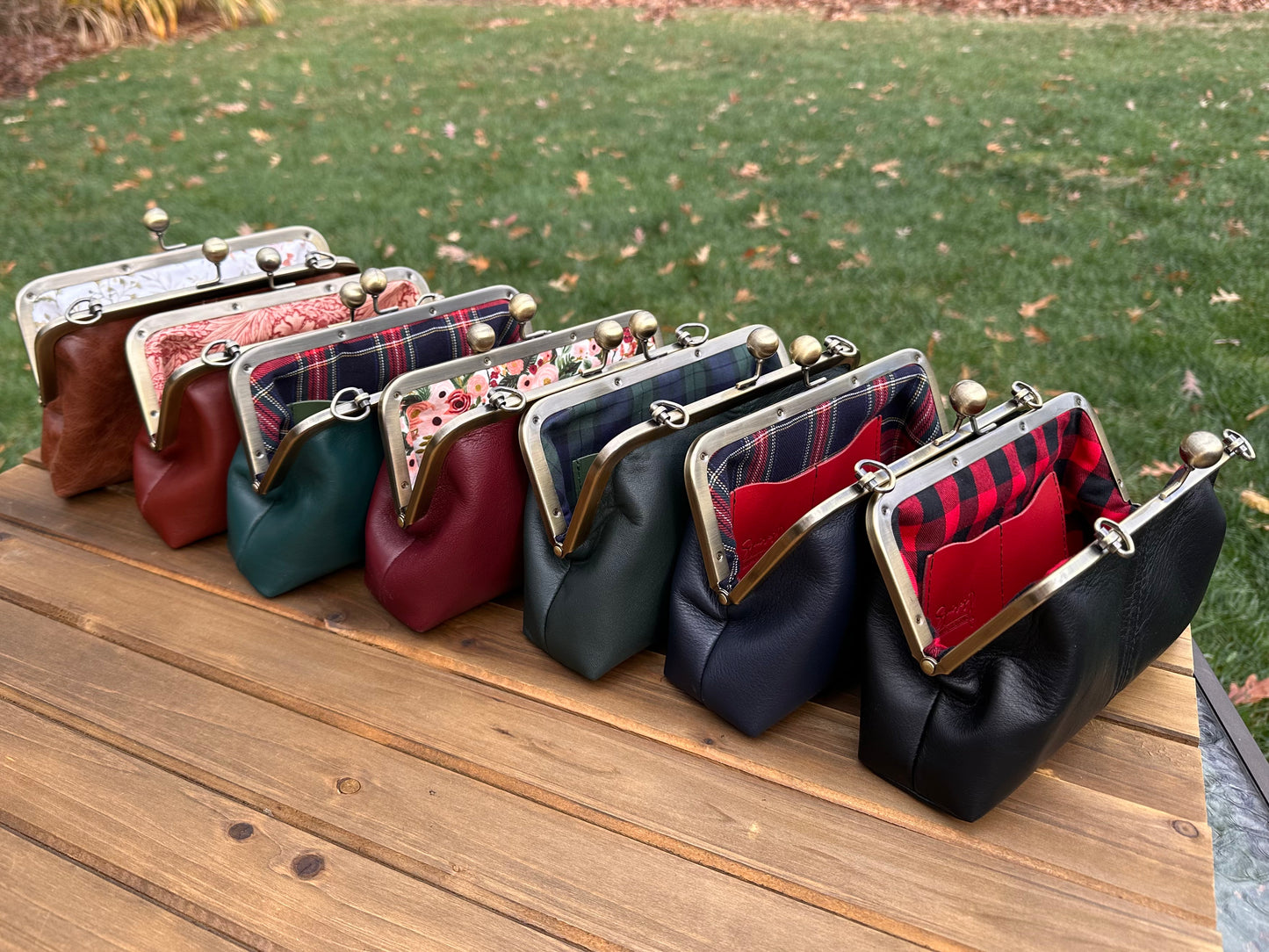 Collection of handcrafted leather kiss lock purses with bronze hardware and chain straps. The interior of leather kiss lock purses with various colorful linings. Includes 2 card slots and space for phone and essentials. Compact and functional design. Wear as clutch, shoulder, or crossbody. Made in Maryland.
