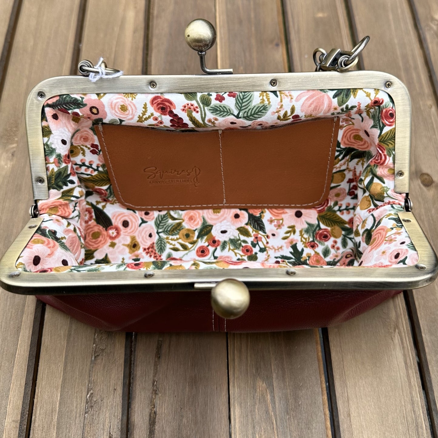 Interior of Burgundy leather kiss lock purse with Pink Floral lining. Includes 2 card slots and space for phone and essentials. Compact and functional design. Made in Maryland.