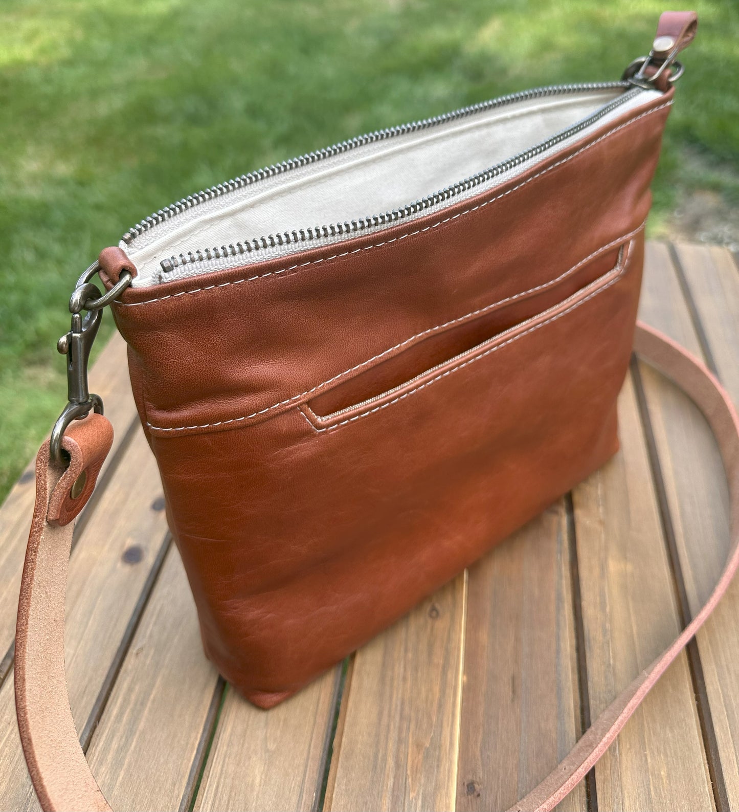 Front open view of a handcrafted Leather Bayside Crossbody bag in Sienna Horween leather, showcasing its rich, warm color, natural grain, solid brass hardware, and full metal zipper. Designed and made in Maryland.