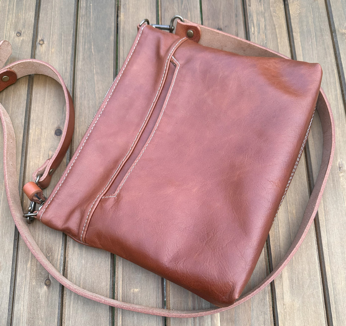 Overhead view of a handcrafted Leather Bayside Crossbody bag in Sienna Horween leather, showcasing its rich, warm color, natural grain, solid brass hardware, and full metal zipper. Designed and made in Maryland.