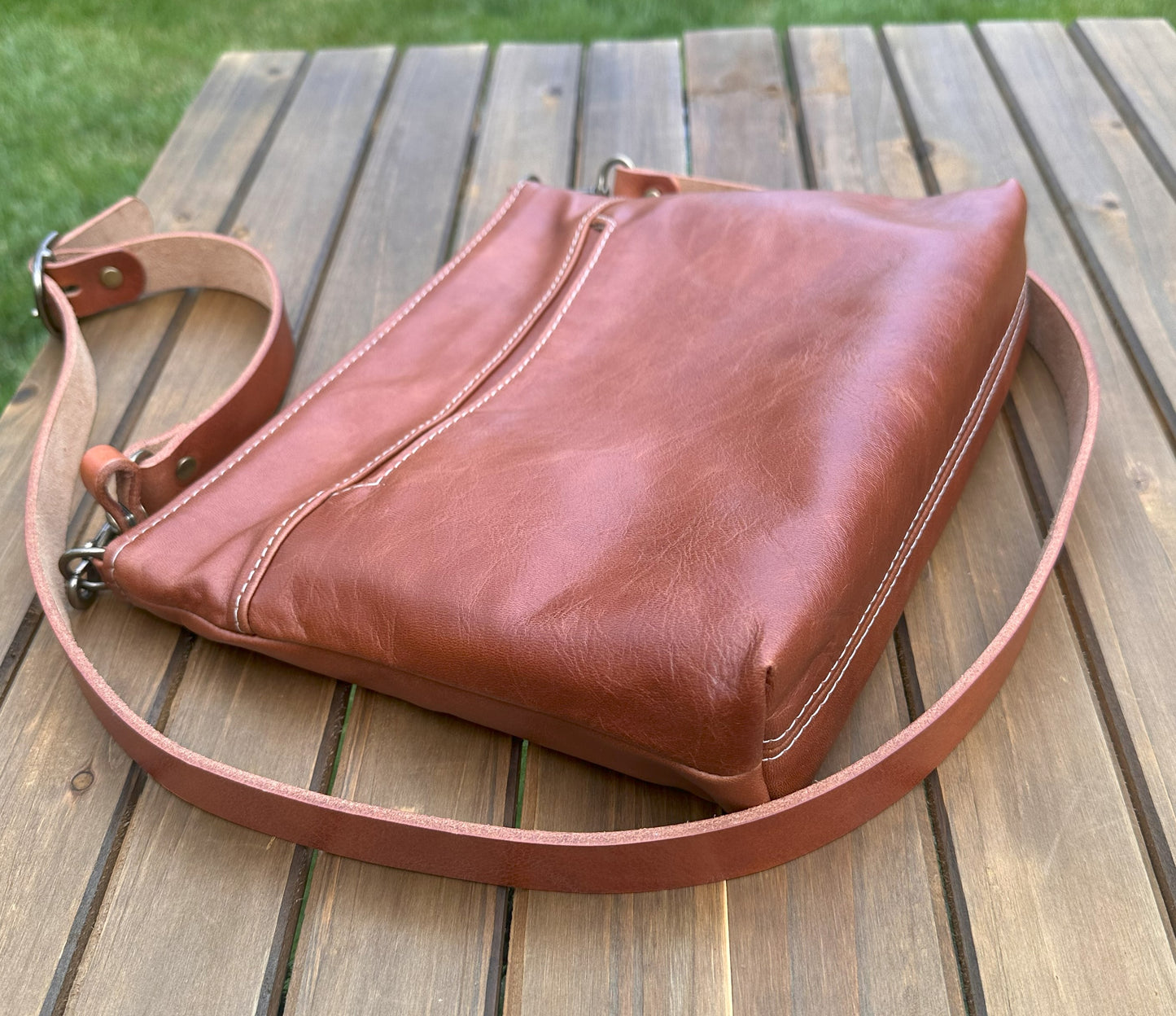 Overhead view of a handcrafted Leather Bayside Crossbody bag in Sienna Horween leather, showcasing its rich, warm color, natural grain, solid brass hardware, and full metal zipper. Designed and made in Maryland.