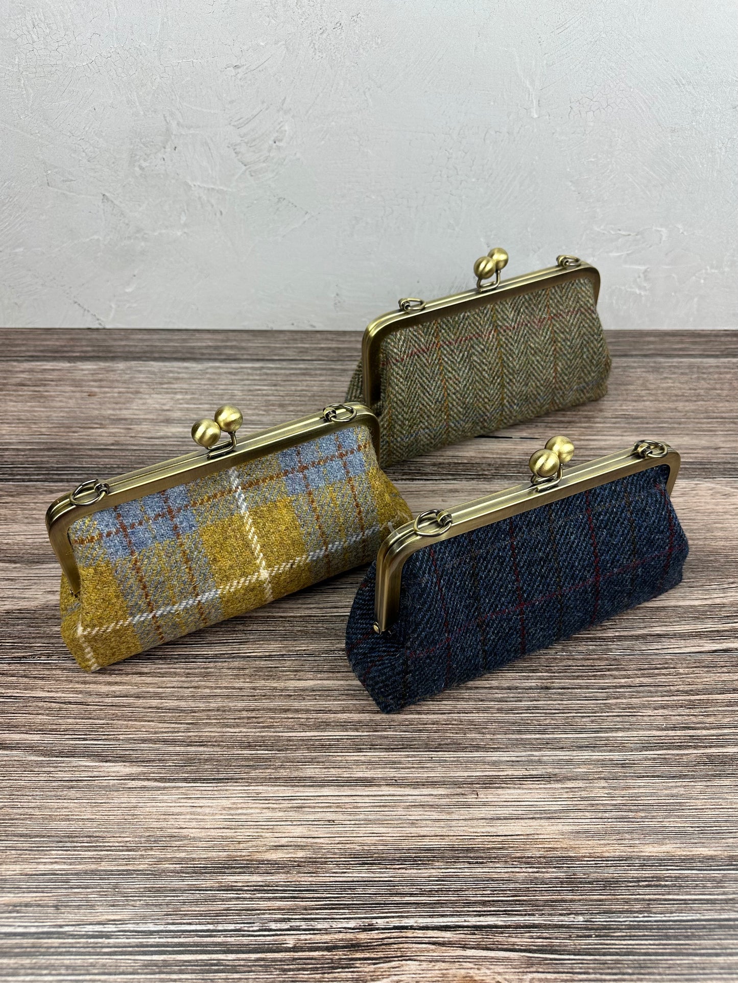 Collection of handcrafted Harris Tweed® kiss lock purses with bronze hardware. Classic clutch style with 2 card slots, fits a phone and small essentials. Wear as a clutch, shoulder bag, or crossbody. Made in Maryland, perfect for special occasions.