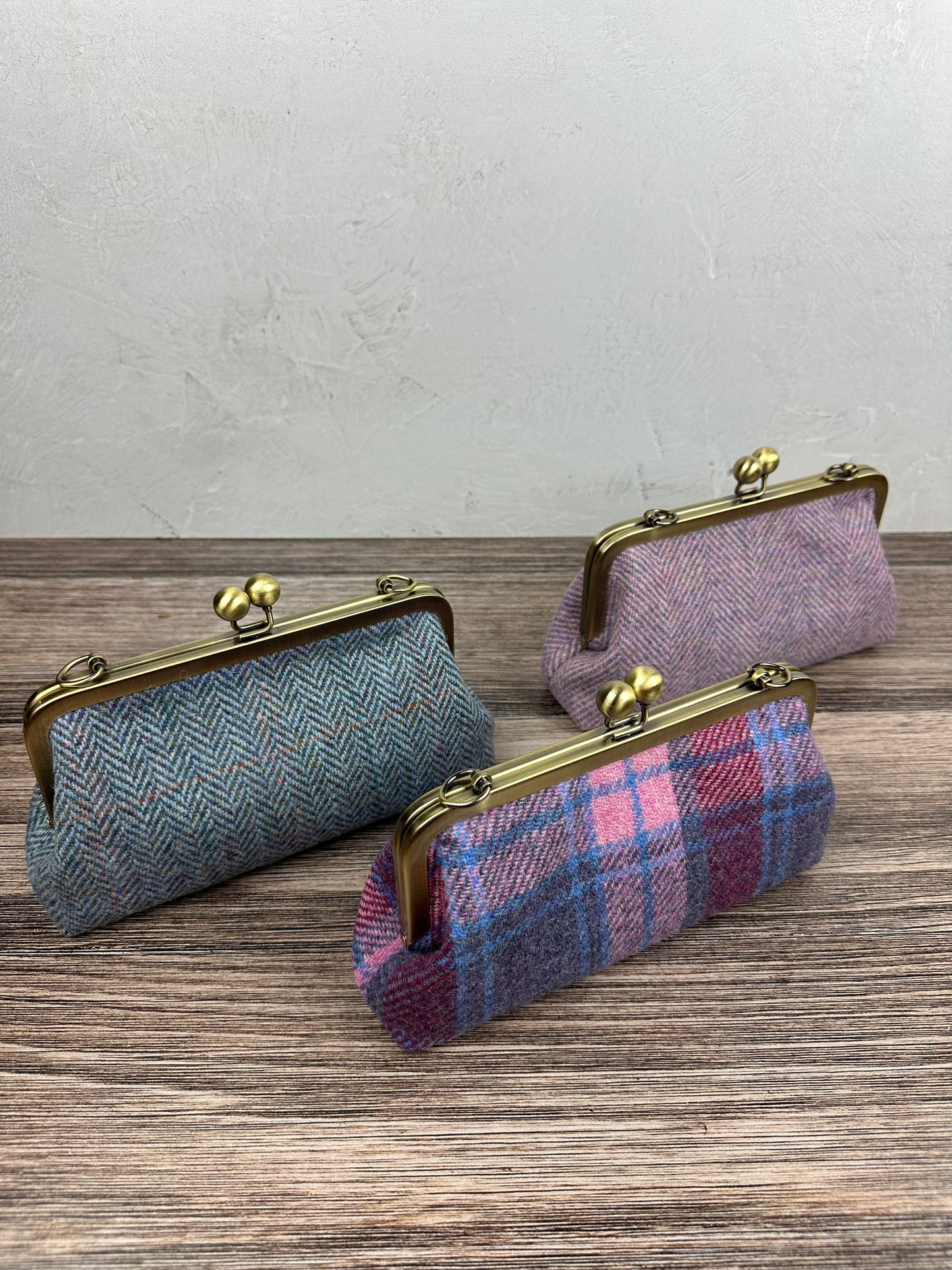 Collection of handcrafted Harris Tweed® kiss lock purses with bronze hardware. Classic clutch style with 2 card slots, fits a phone and small essentials. Wear as a clutch, shoulder bag, or crossbody. Made in Maryland, perfect for special occasions.