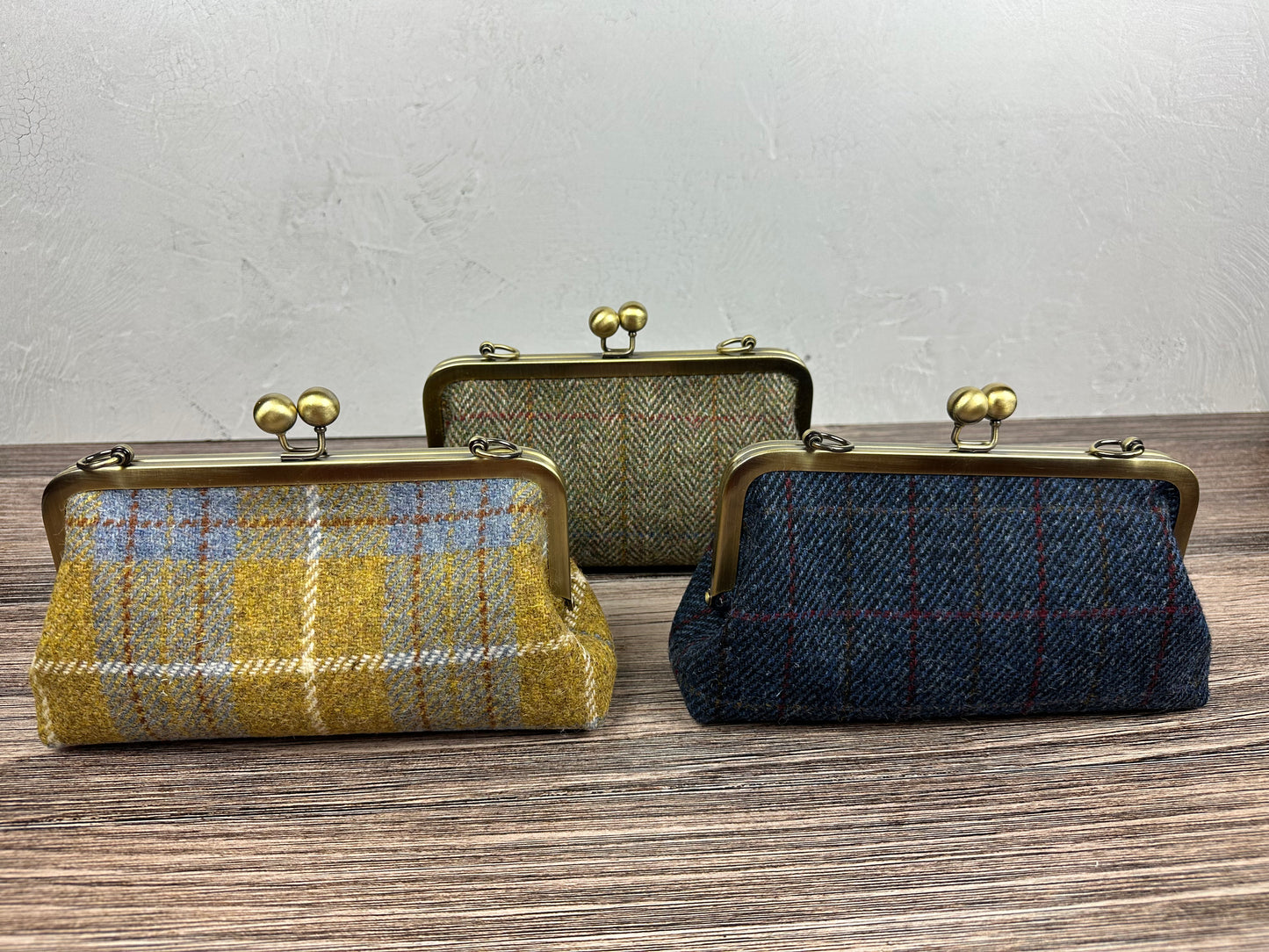 Collection of handcrafted Harris Tweed® kiss lock purses with bronze hardware. Classic clutch style with 2 card slots, fits a phone and small essentials. Wear as a clutch, shoulder bag, or crossbody. Made in Maryland, perfect for special occasions.