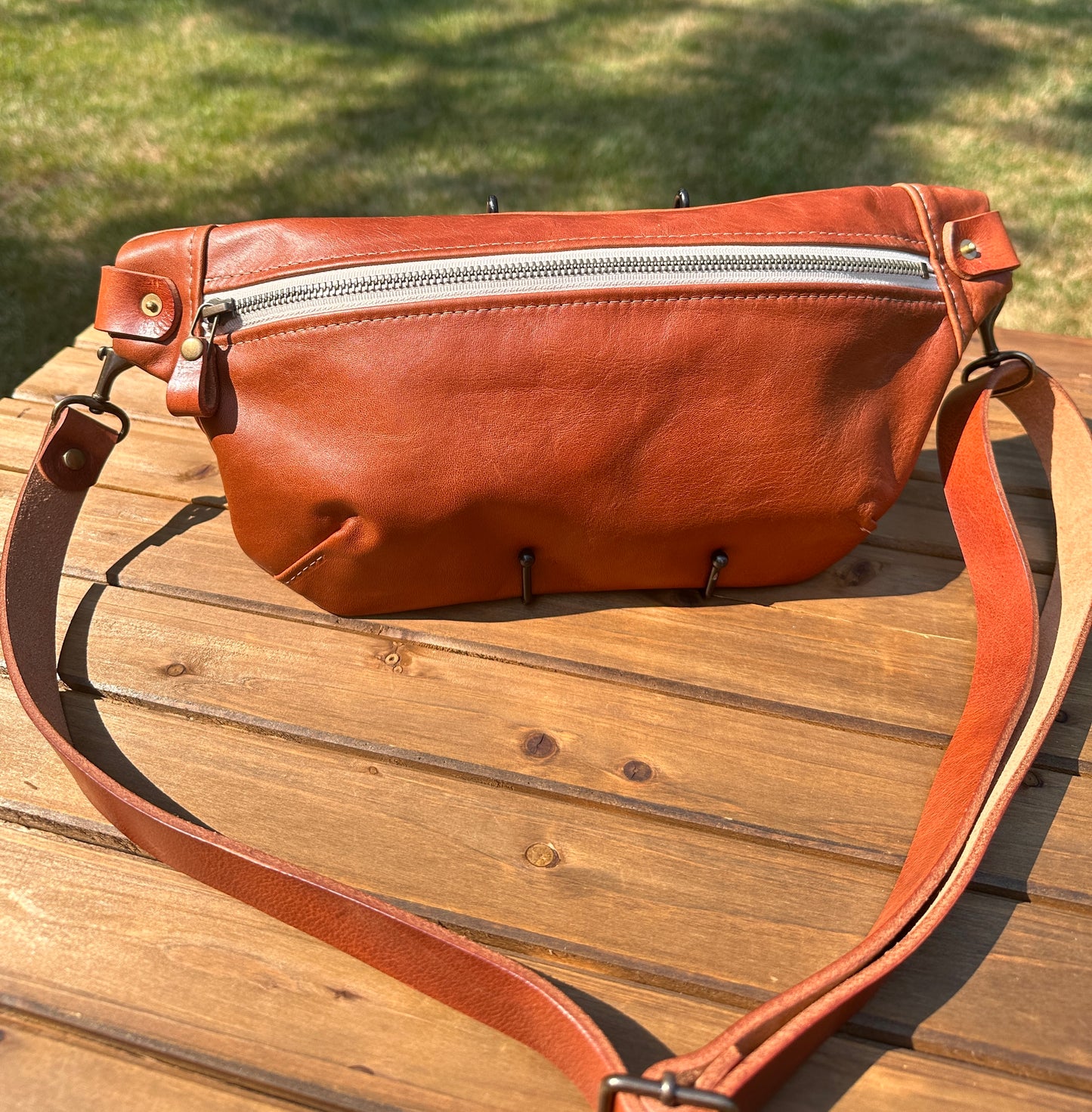 Front view of Leather Spinnaker Sling bag in Sienna with bronze hardware, linen interior, and front zipper. Unisex slim crossbody sling handmade in Maryland.