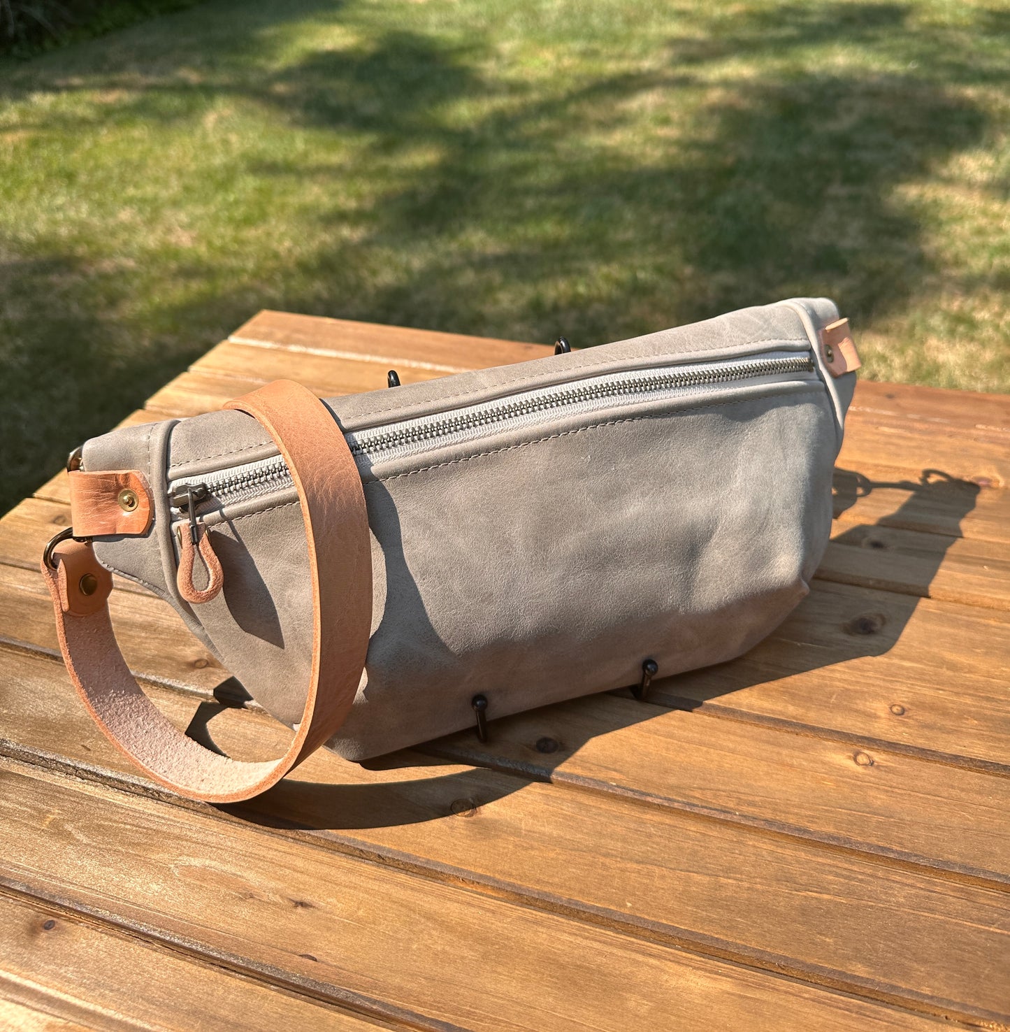 Front view of Leather Spinnaker Sling bag in Distressed Gray Leather with bronze hardware, linen interior, and front zipper. Unisex slim crossbody sling handmade in Maryland.