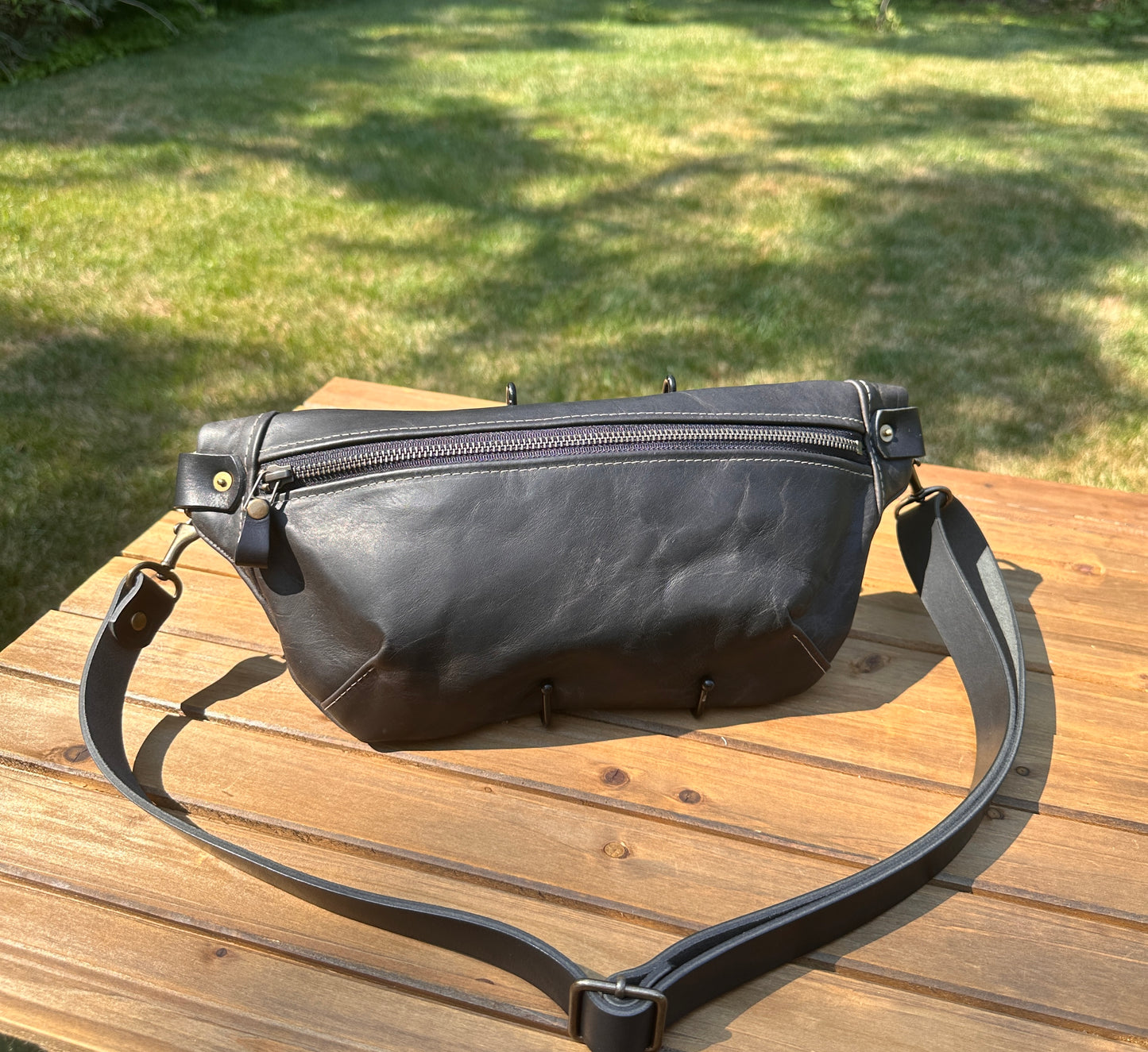 Front view of Leather Spinnaker Sling bag in Rustic Charcoal Dublin Leather with bronze hardware, linen interior, and front zipper. Unisex slim crossbody sling handmade in Maryland.