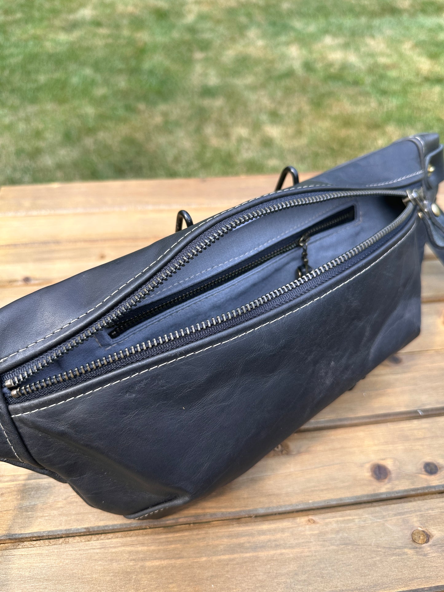 Interior view of Leather Spinnaker Sling bag in Rustic Charcoal Dublin Leather with linen lining and interior zipper pocket. Slim and practical leather sling bag handcrafted in Maryland.