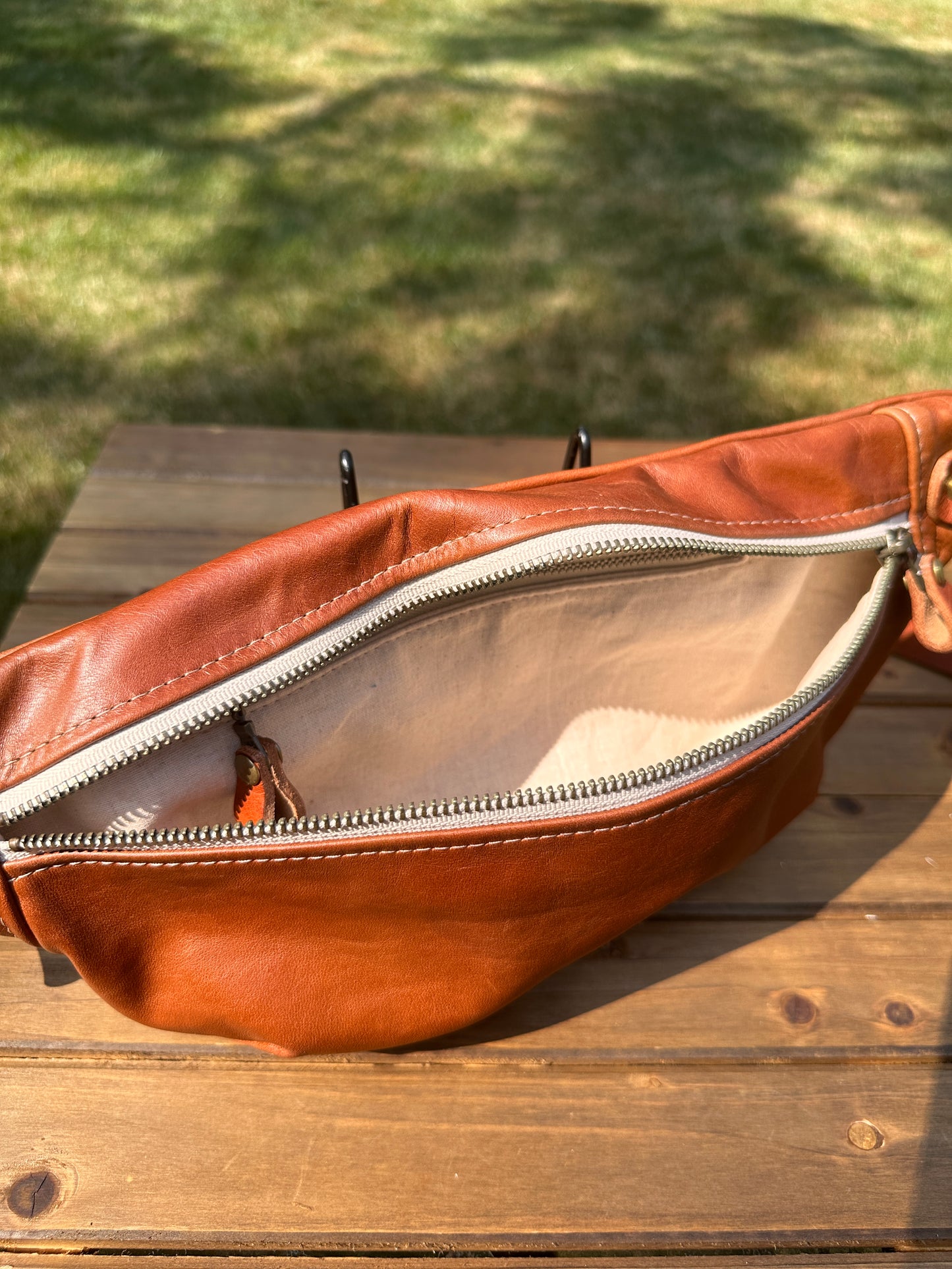Interior view of Leather Spinnaker Sling bag in Sienna Leather with linen lining and interior zipper pocket. Slim and practical leather sling bag handcrafted in Maryland.