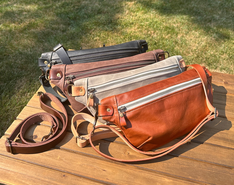 Collection of handcrafted leather Spinnaker Sling bags in rustic and smooth finishes, featuring full-grain leather, linen interior, and solid brass hardware. Handcrafted in Maryland.