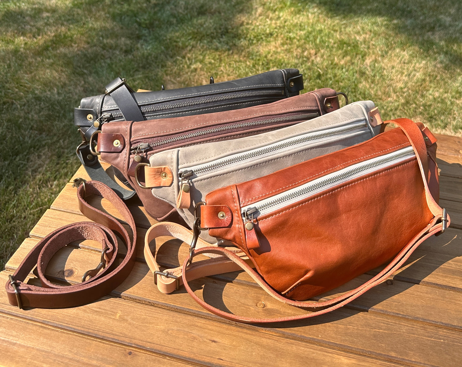Collection of handcrafted leather Spinnaker Sling bags in rustic and smooth finishes, featuring full-grain leather, linen interior, and solid brass hardware. Handcrafted in Maryland.