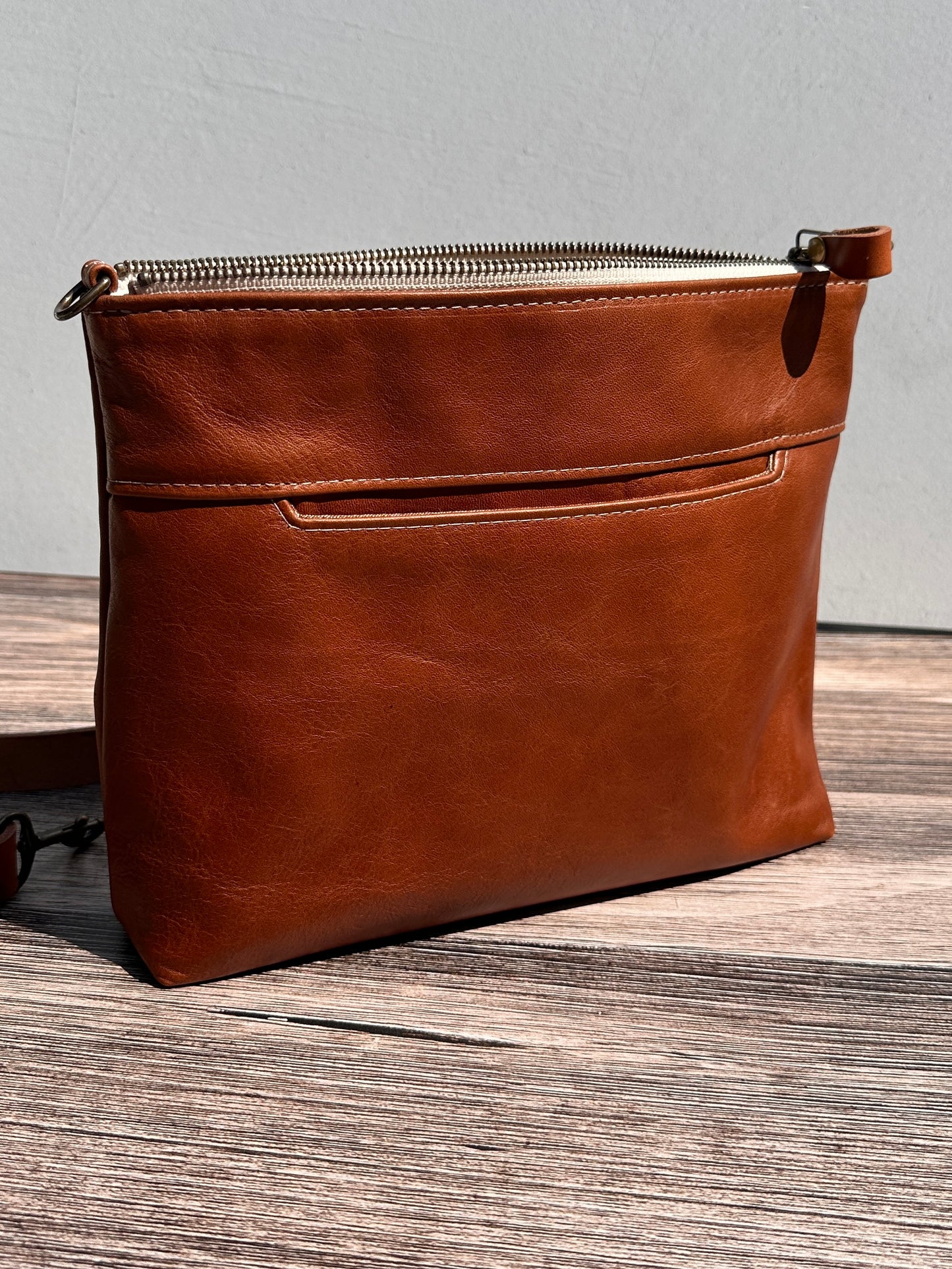 Front view of a handcrafted Leather Bayside Crossbody bag in Sienna Horween leather, showcasing its rich, warm color, natural grain, solid brass hardware, and full metal zipper. Designed and made in Maryland.