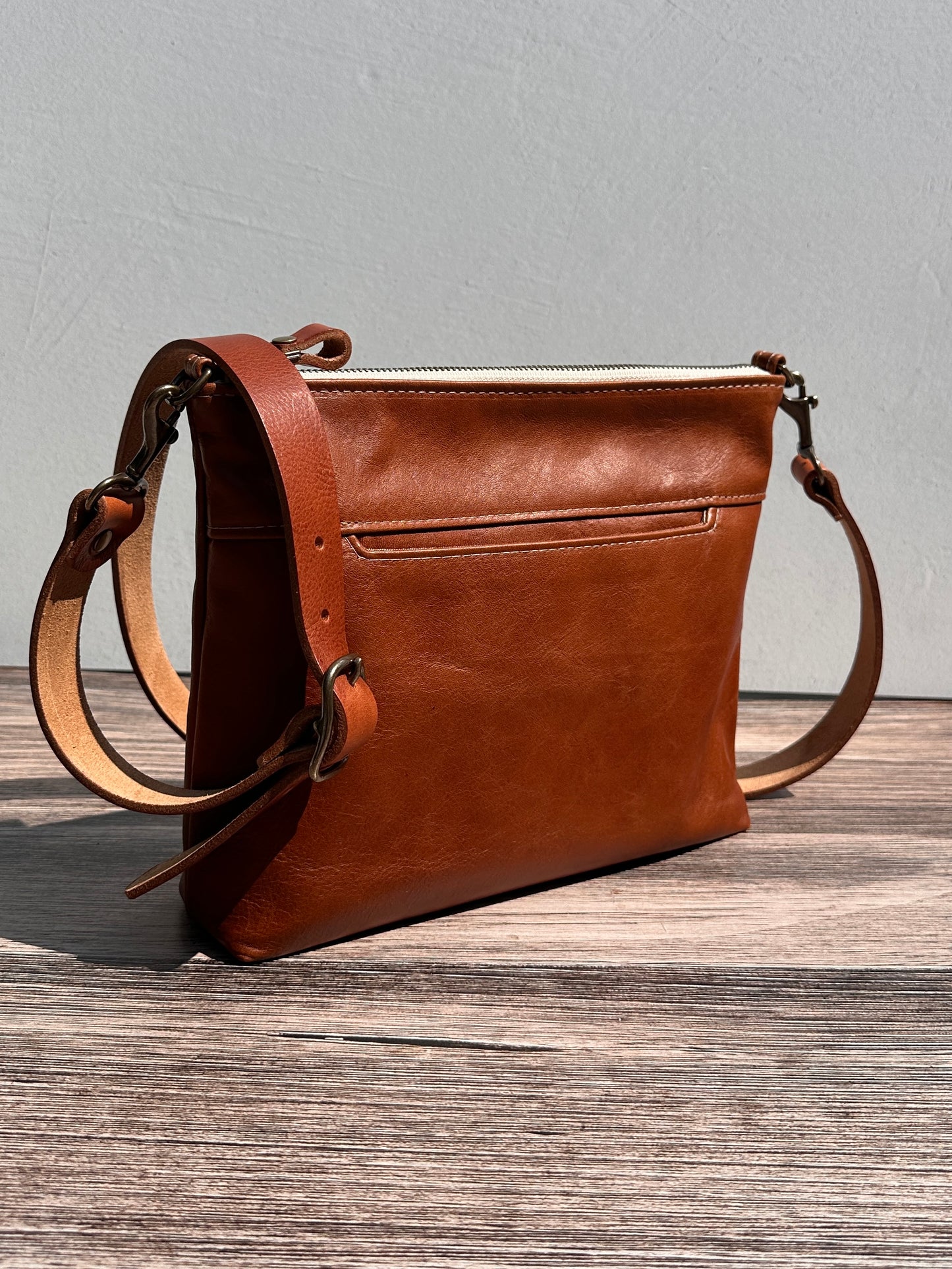 Front view of a handcrafted Leather Bayside Crossbody bag in Sienna Horween leather, showcasing its rich, warm color, natural grain, solid brass hardware, and full metal zipper. Designed and made in Maryland.