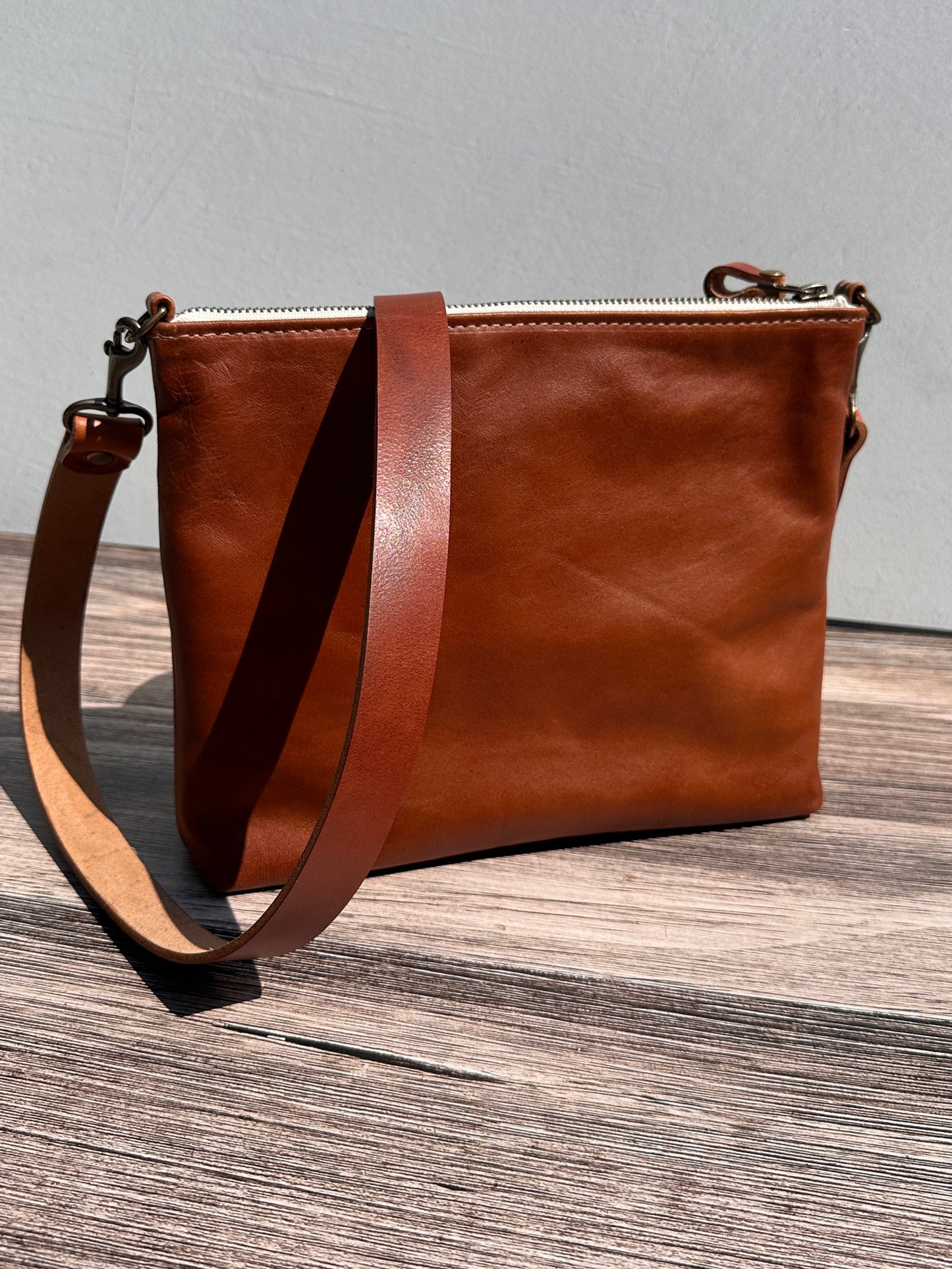 Back view of a handcrafted Leather Bayside Crossbody bag in Sienna Horween leather, showcasing its rich, warm color, natural grain, solid brass hardware, and full metal zipper. Designed and made in Maryland.