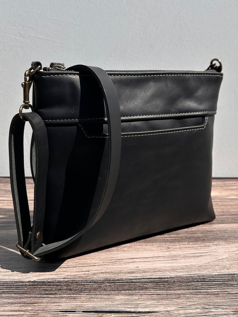 Front view of a handcrafted Leather Bayside Crossbody bag in Bomber Jacket Black Horween leather, showcasing its rich, warm color, natural grain, solid brass hardware, and full metal zipper. Designed and made in Maryland.