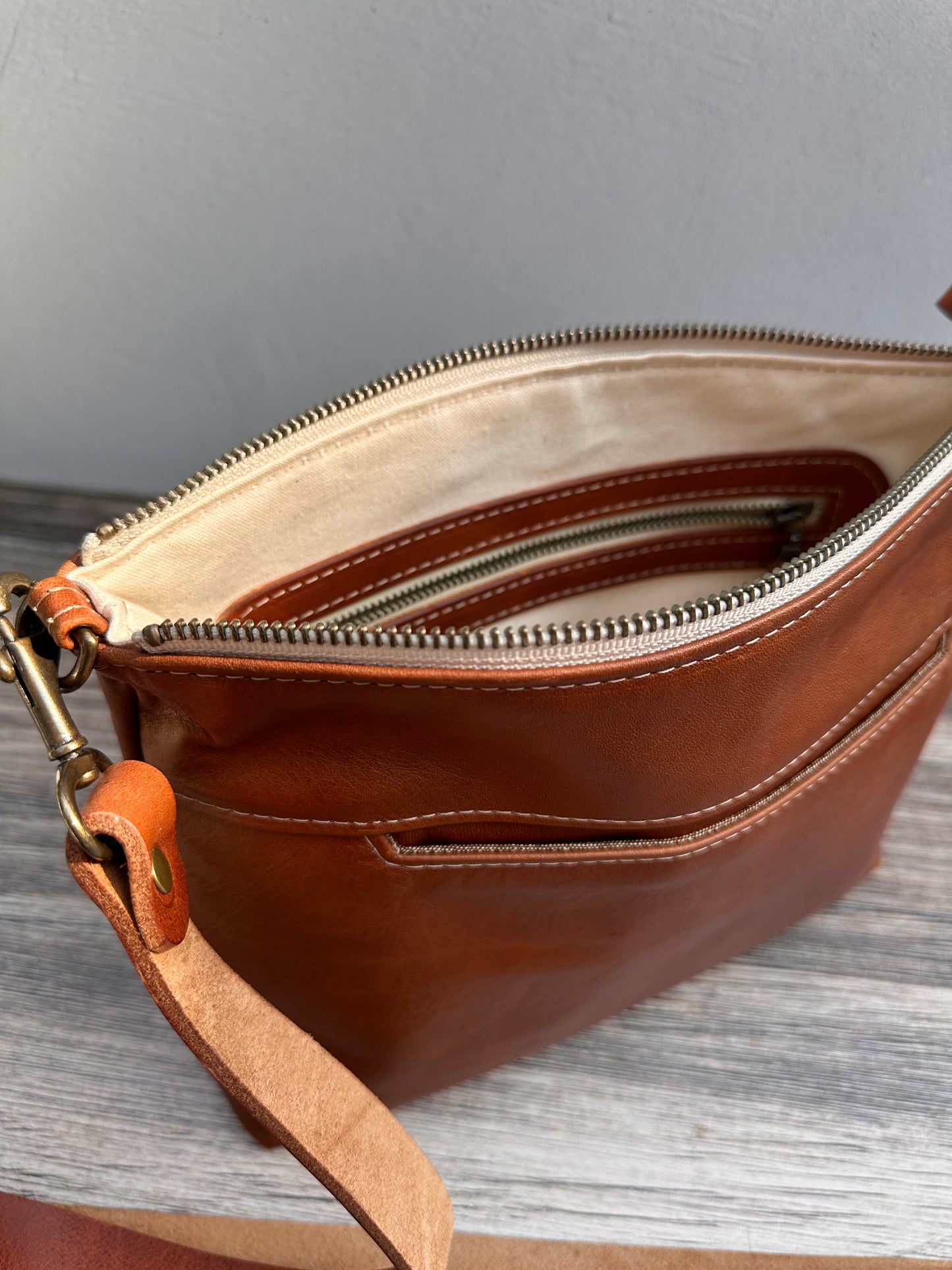 Front open view of a handcrafted Leather Bayside Crossbody bag in Sienna Horween leather, showcasing its rich, warm color, natural grain, solid brass hardware, and full metal zipper. Designed and made in Maryland.