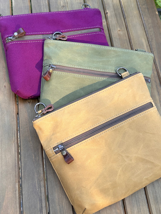 Collection of handcrafted Canvas Bayside Slim Crossbody Bags in waxed canvas, and solid canvas styles, with full canvas lining and adjustable vegetable-tanned leather straps.