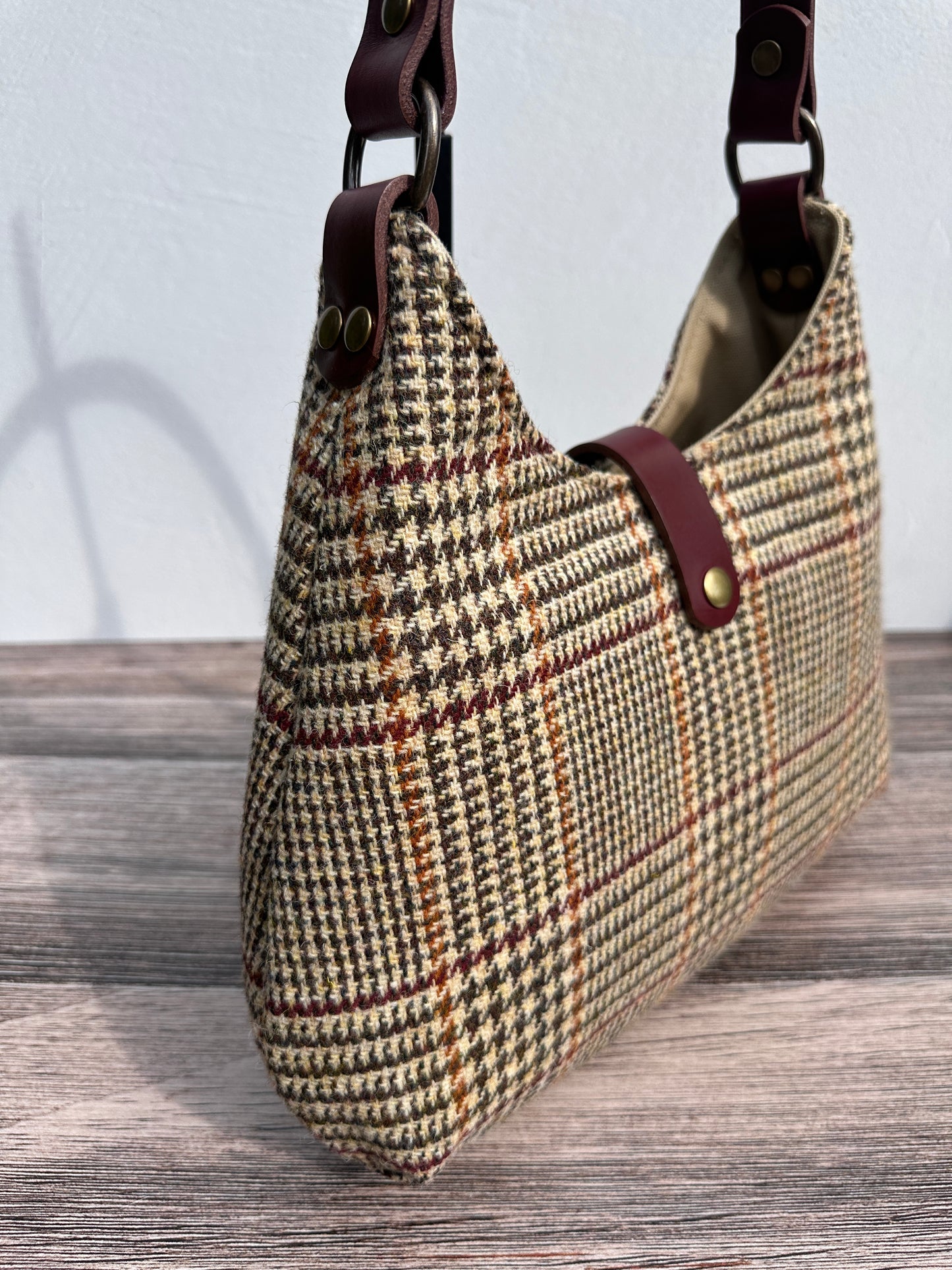 Close up view Glen Plaid Harris Tweed® Rhode River Shoulder Bags, Bordeaux Leather with Antique Brass Hardware. Handcrafted in Maryland