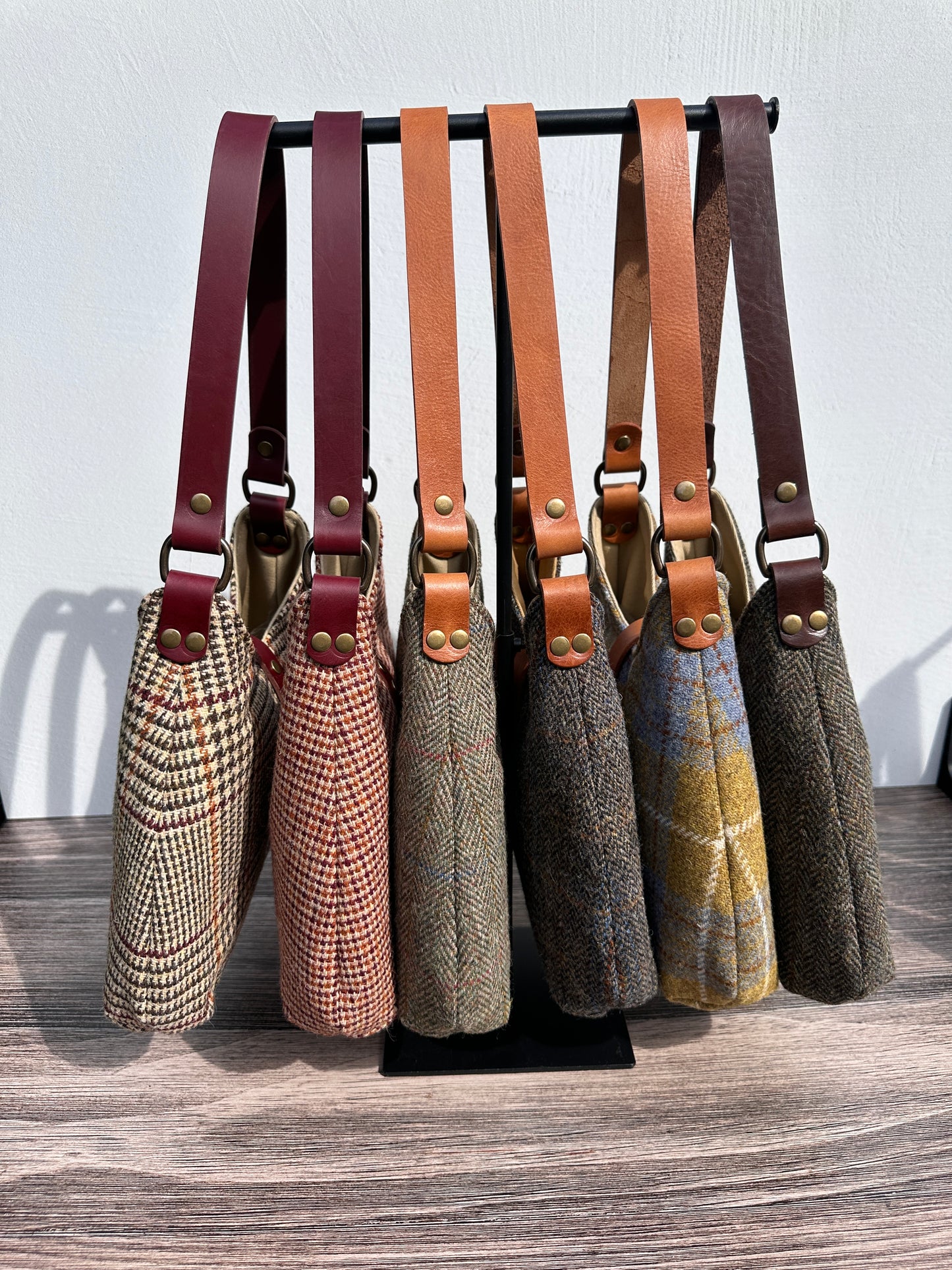 Side view of Harris Tweed® Rhode River Shoulder Bags six bags, with different prints and leather combos paired with Antique Brass Hardware. Handcrafted in Maryland