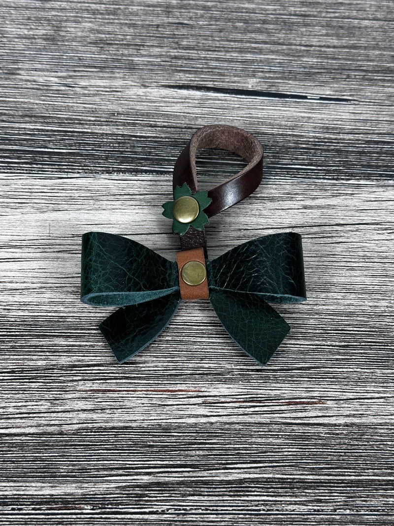 Green Leather bow purse charm with snap closure styled on a leather shoulder bag.