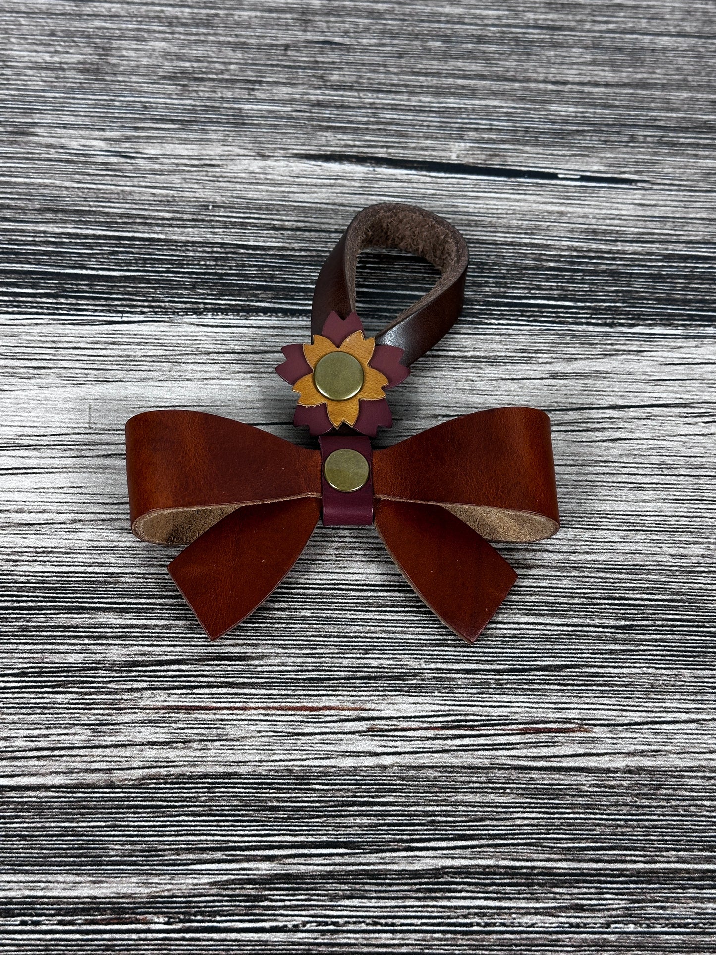 Cognac Leather bow purse charm with snap closure styled on a leather shoulder bag.