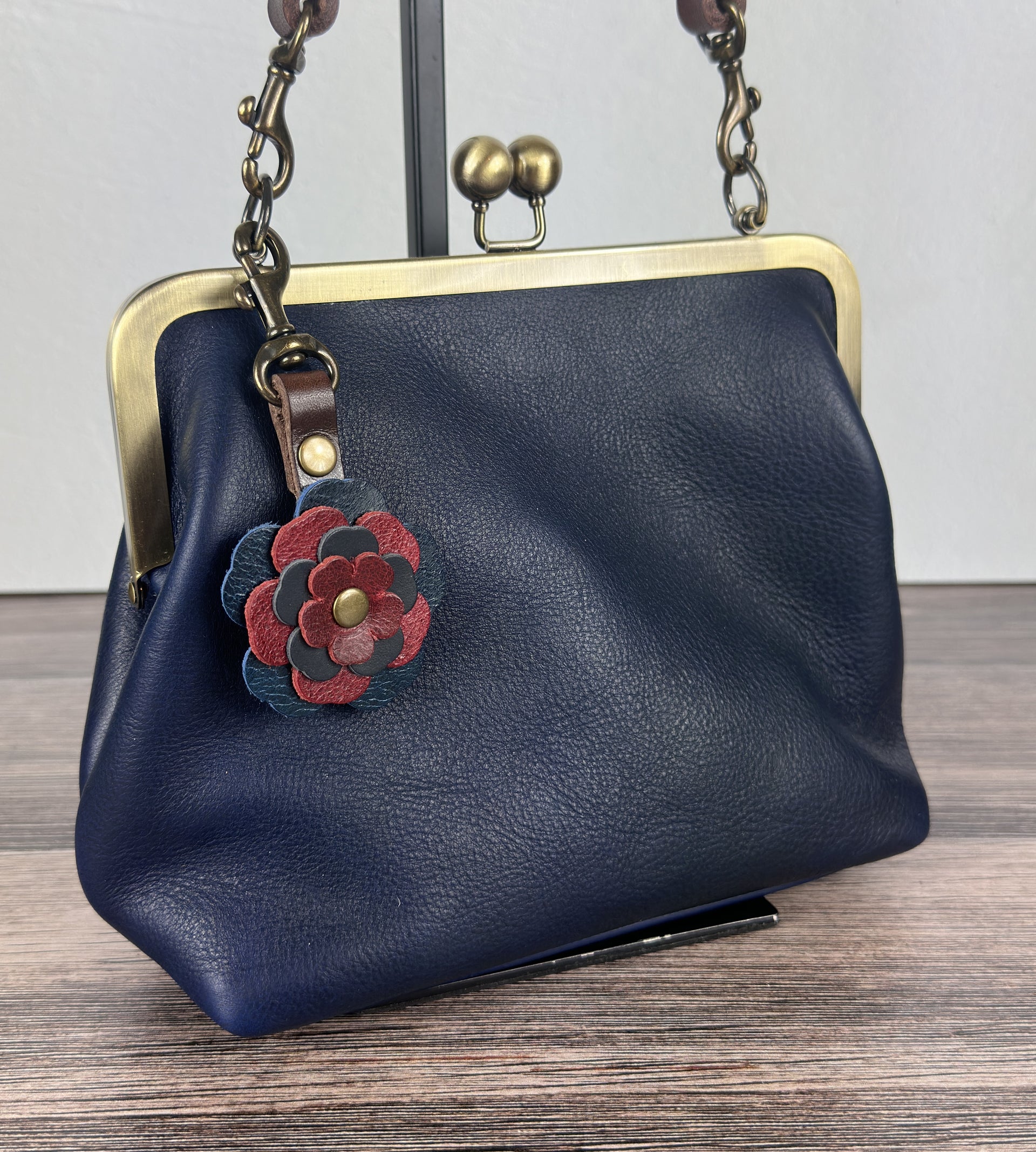 Leather flower bag charm on Ink Blue Leather Princess Anne Kiss Lock Bag – handcrafted leather accessory.