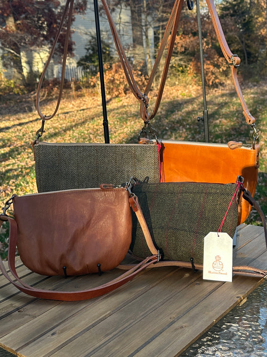 Collection of Holland Island Crossbody bags Sienna Leather, Green Twill with overcheck Harris Tweed®, Acorn Leather, and Green Herringbone Harris Tweed®.