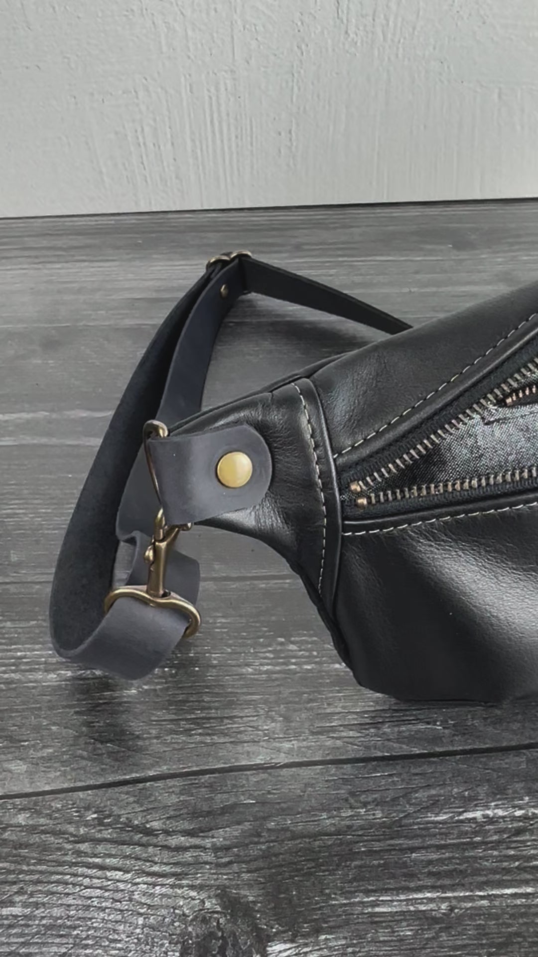 Side view of Leather Spinnaker Sling bag in Black with bronze hardware, Grey linen interior, interior Zipper, and front zipper. Unisex slim crossbody sling handmade in Maryland.