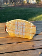 The Seashell Pouch in Yellow and Blue Plaid Harris Tweed® has a curved top and flat base that stands up on its own, lined with natural heavy canvas.